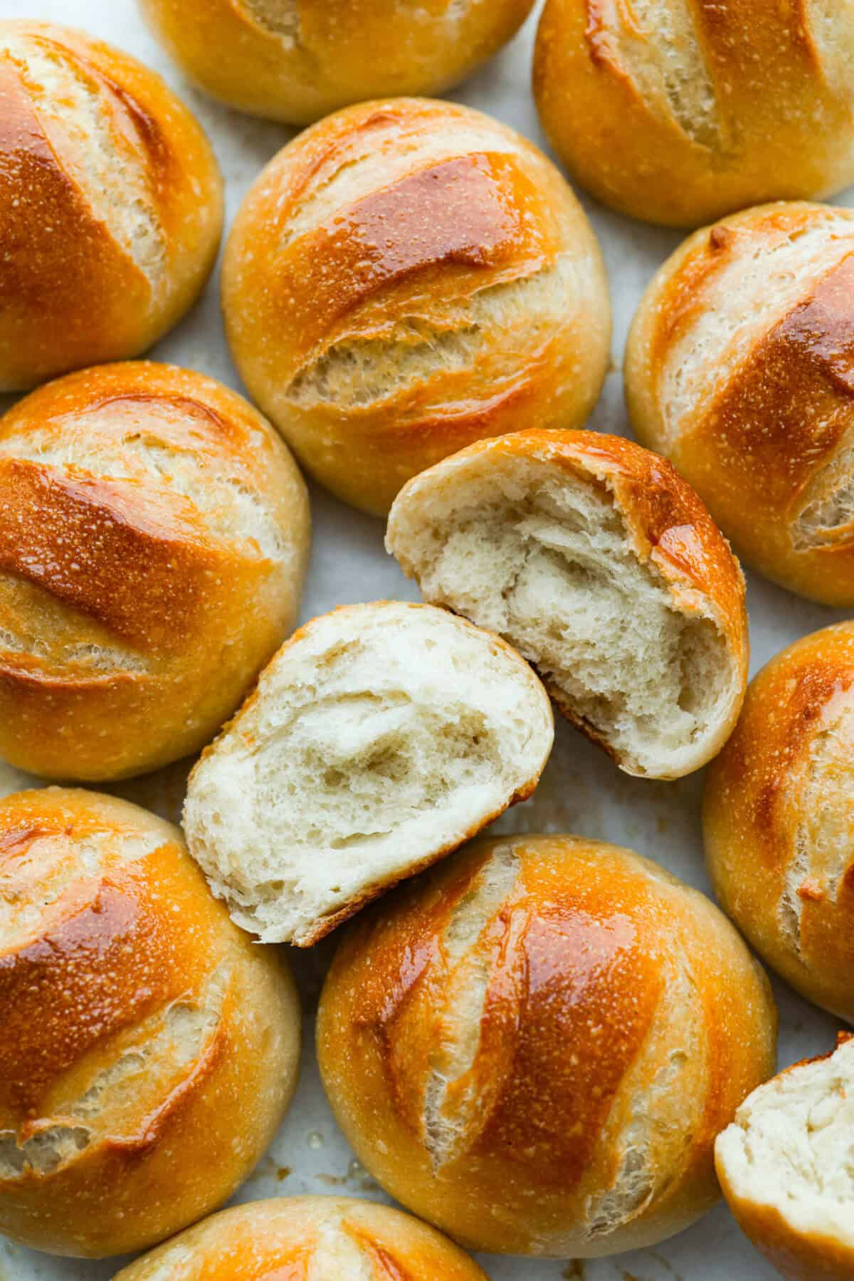 French bread rolls all on a surface with one split in half so we can see the soft center and crunchy outside. 
