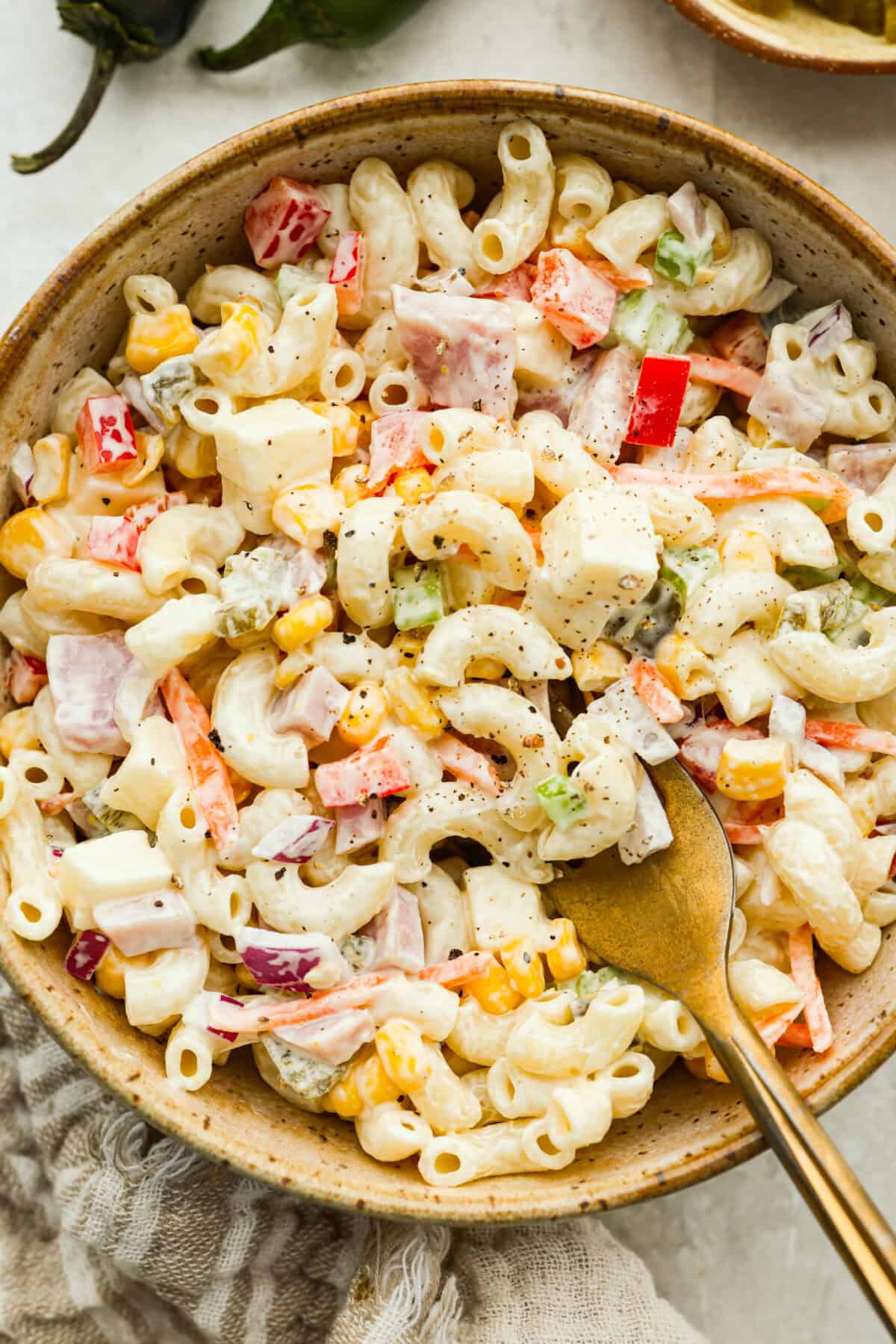Serving of Mexican macaroni salad in a bowl with a gold fork. 