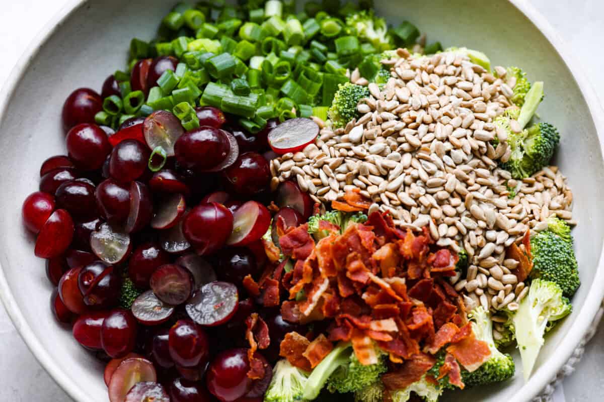 Broccoli grape salad is the crunchy, juicy, smoky combo nobody expects but everyone loves. Sweet grapes, crisp broccoli, smoky bacon, and a tangy lemon dressing come together in just 20 minutes! All of the salad ingredients added to a bowl.