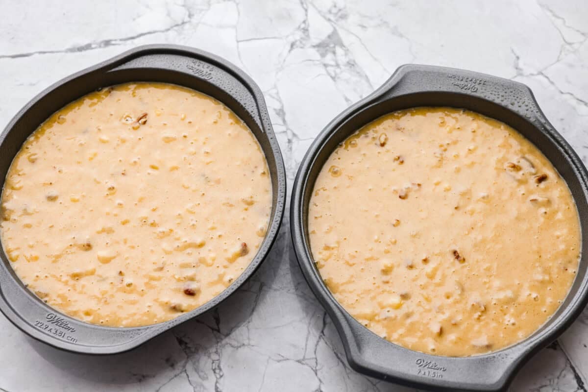 If you’ve never had hummingbird cake, just know it’s one of those cakes people take a bite of and immediately ask for the recipe. It’s soft, sweet, packed with banana and pineapple, and topped with a cream cheese frosting that is to die for! Two round cake pans filled with batter ready to go in the oven.