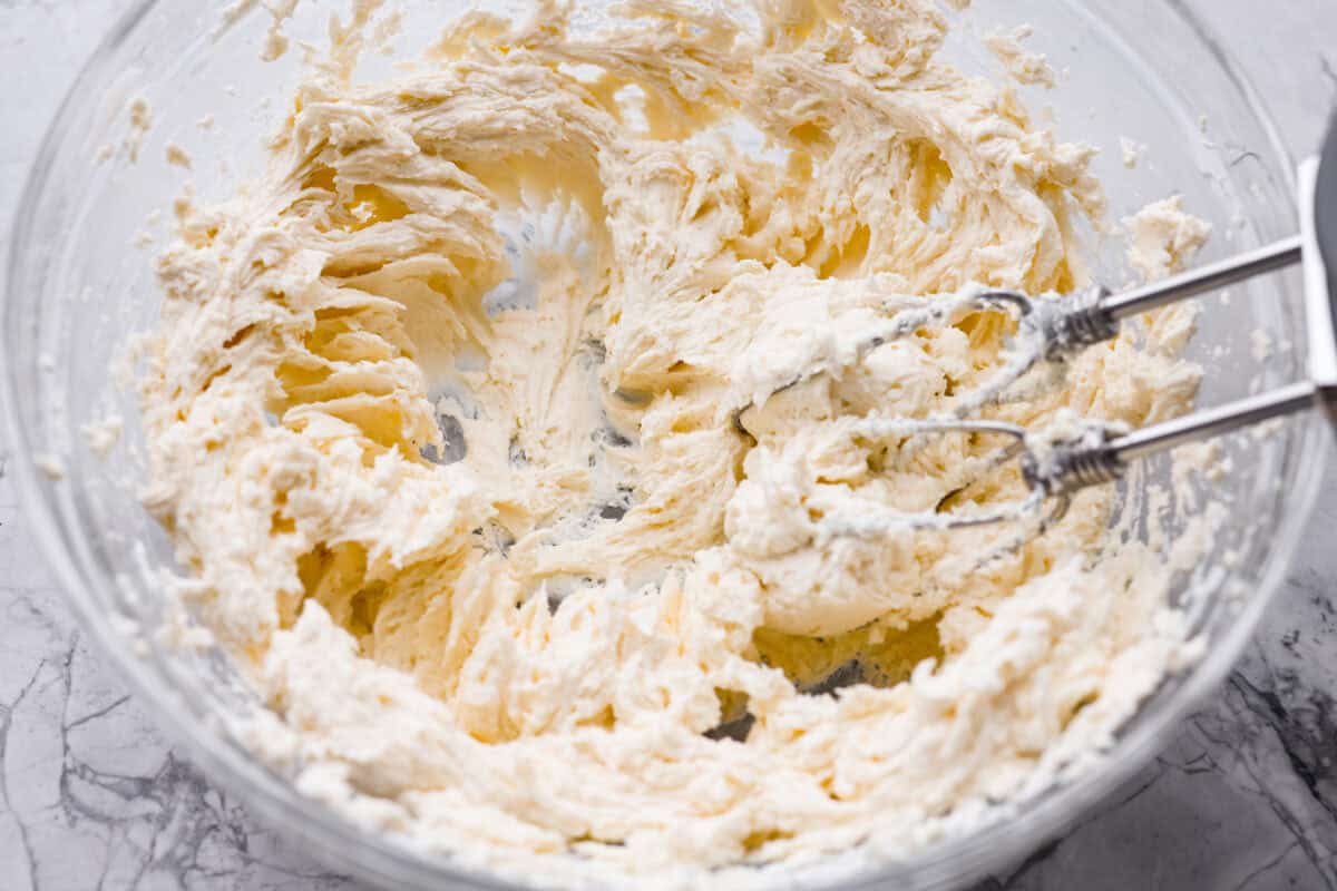 If you’ve never had hummingbird cake, just know it’s one of those cakes people take a bite of and immediately ask for the recipe. It’s soft, sweet, packed with banana and pineapple, and topped with a cream cheese frosting that is to die for! Cream cheese and butter mixed together in a mixing bowl with a hand mixer.