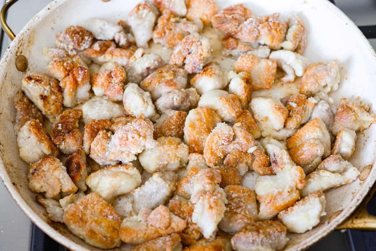 Coated chicken cooking in a skillet.