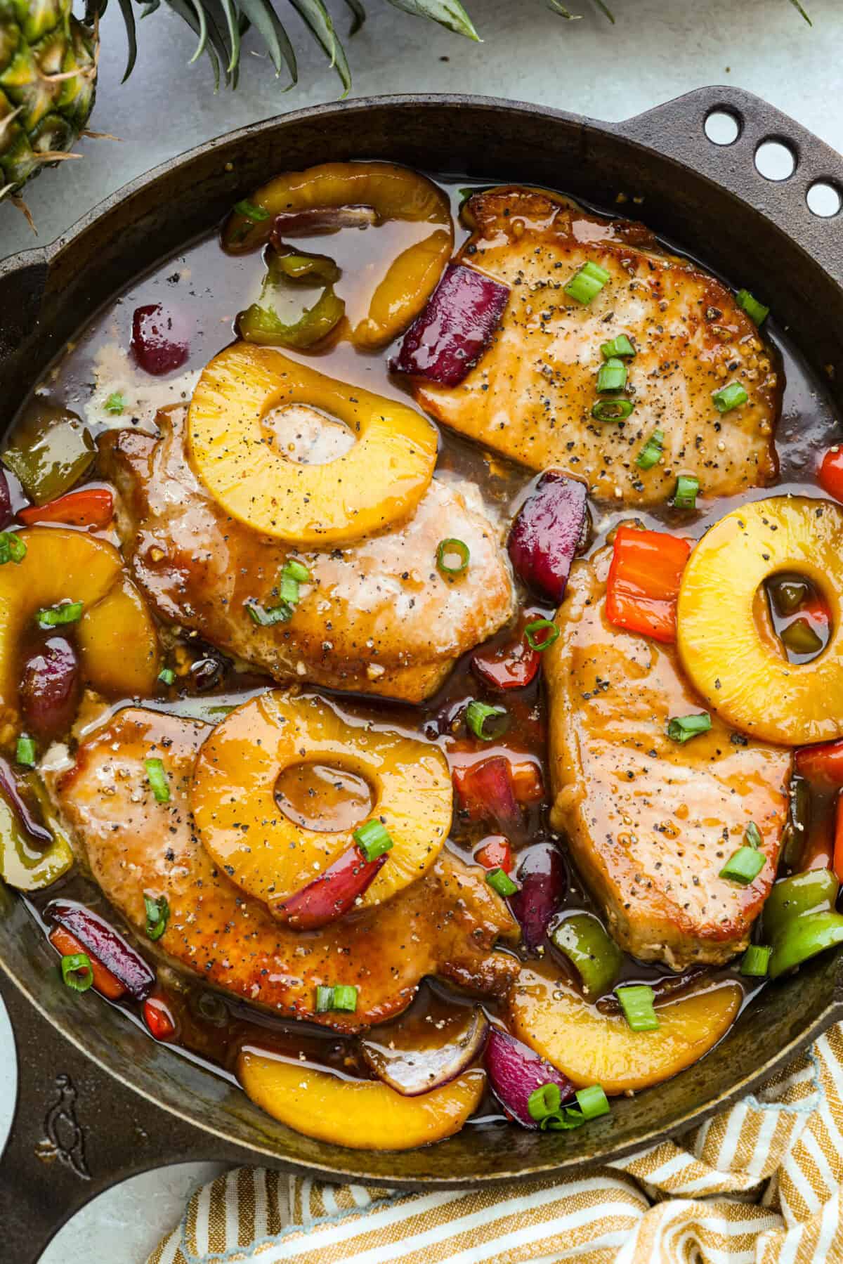 My Hawaiian pork chops are sweet, savory, colorful, and so easy! Pork chops simmer in a pineapple sauce with bell peppers, making the whole skillet irresistible. Serve it over rice so you can catch every drop of that delicious sauce. Skillet full of Hawaiian pork chops in a pineapple sauce.