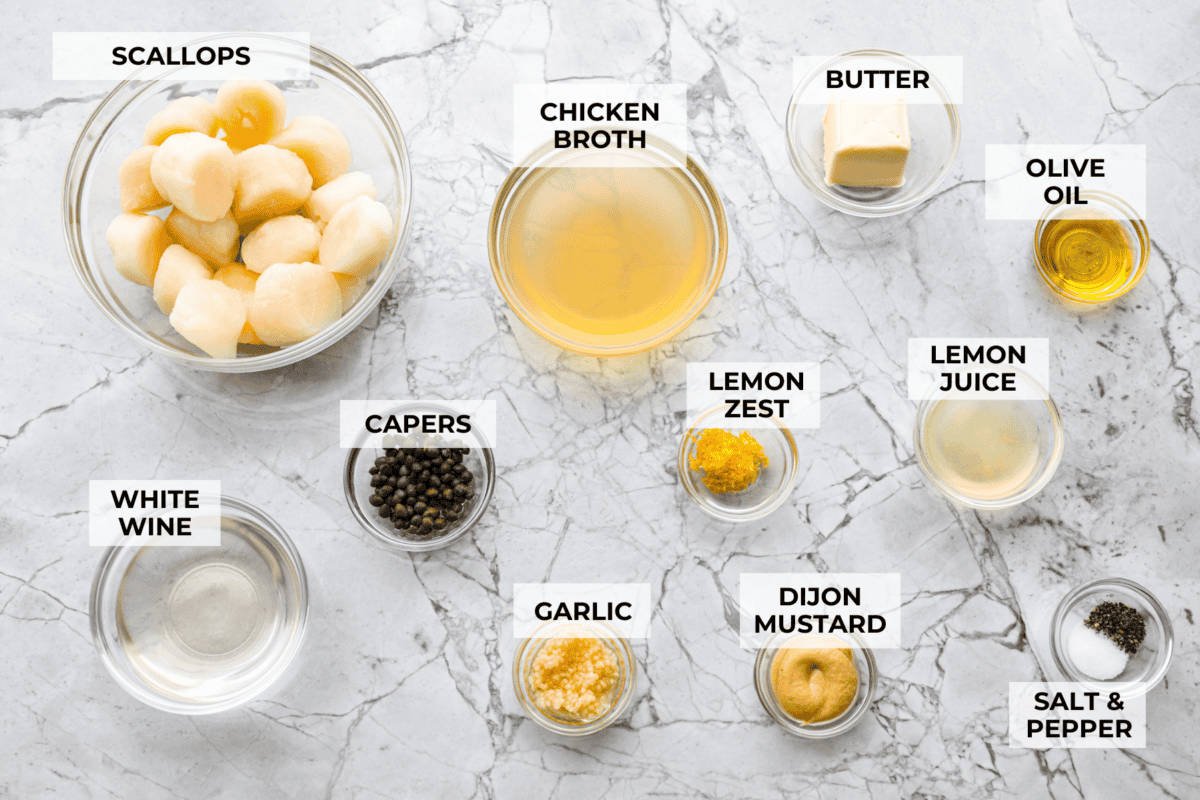 My pan seared scallops recipe has been a reader favorite for years, and one bite will show you why. The buttery golden scallops with that bright, fresh lemon flavor are what make this recipe stand out from all the others. Overhead shot of labeled pan seared scallops ingredients.