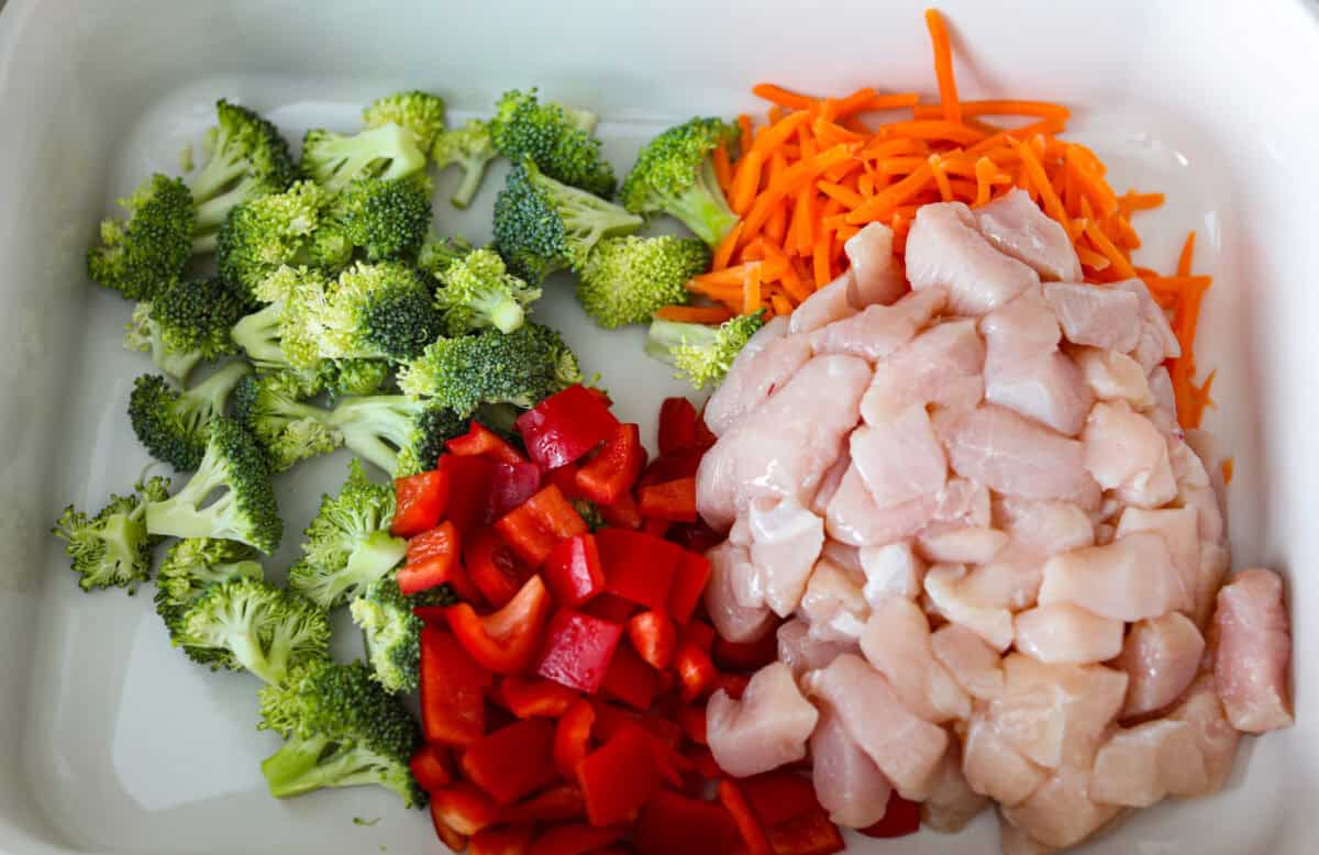 I kept seeing this dump and bake ramen all over my feed and finally had to try it for myself! Turning family favorite ramen into a cozy baked dinner was an immediate hit! It's so good with tender noodles, colorful veggies, and a savory sauce! Chopped veggies and diced chicken in a baking dish.