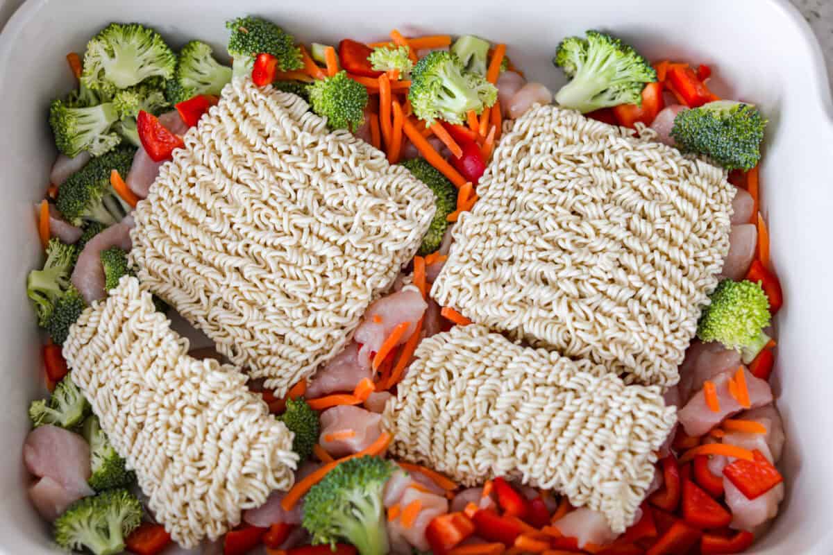 I kept seeing this dump and bake ramen all over my feed and finally had to try it for myself! Turning family favorite ramen into a cozy baked dinner was an immediate hit! It's so good with tender noodles, colorful veggies, and a savory sauce! Ramen noodles added to the baking dish with the chicken and veggies.