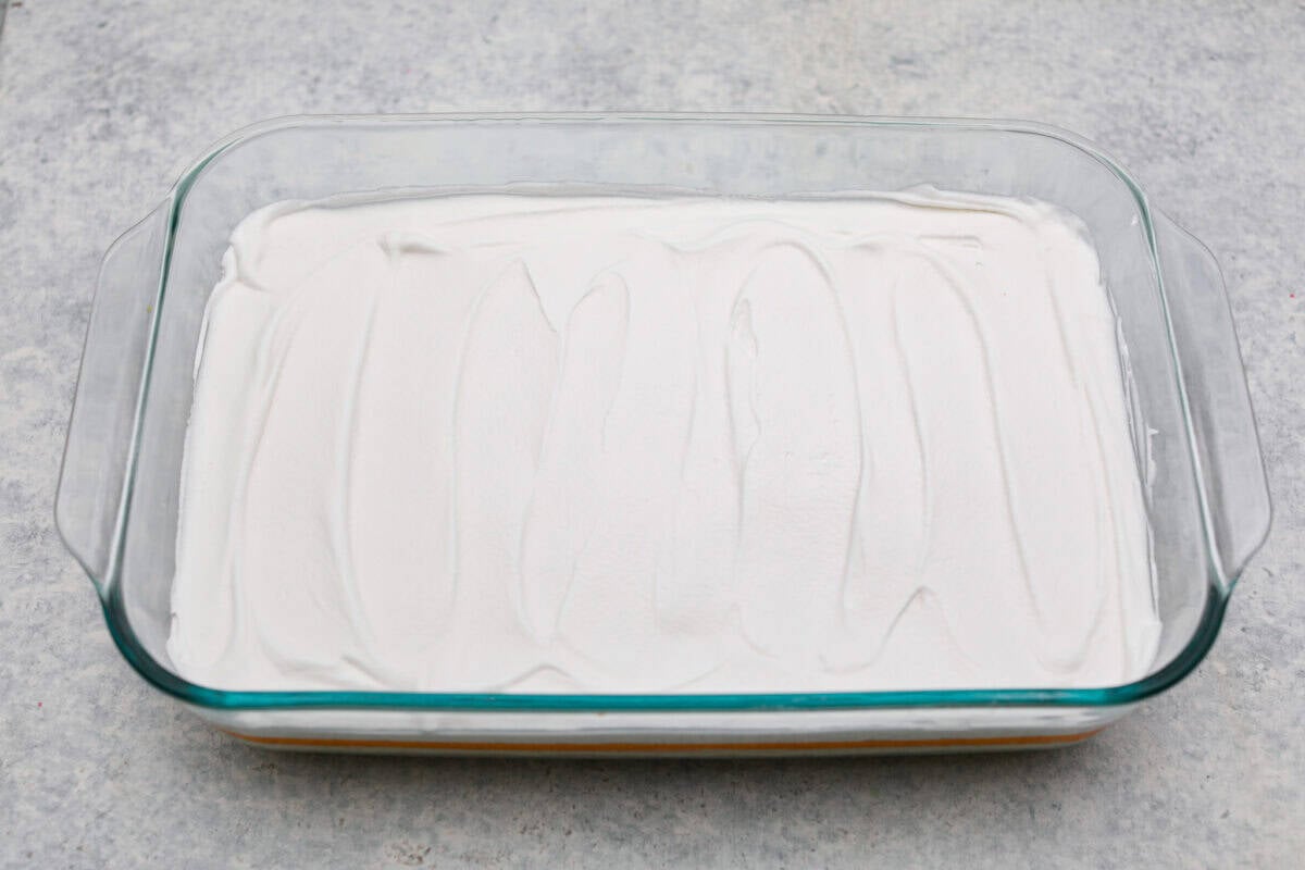 Orange creamsicle lush is sunshine in dessert form! With creamy orange layers, a buttery golden Oreo crust, and bright fresh citrus flavor, this easy no-bake dessert is a fun twist on my popular Lemon Lush that’s perfect for summer. Whipped topping layer on top of the orange layers.