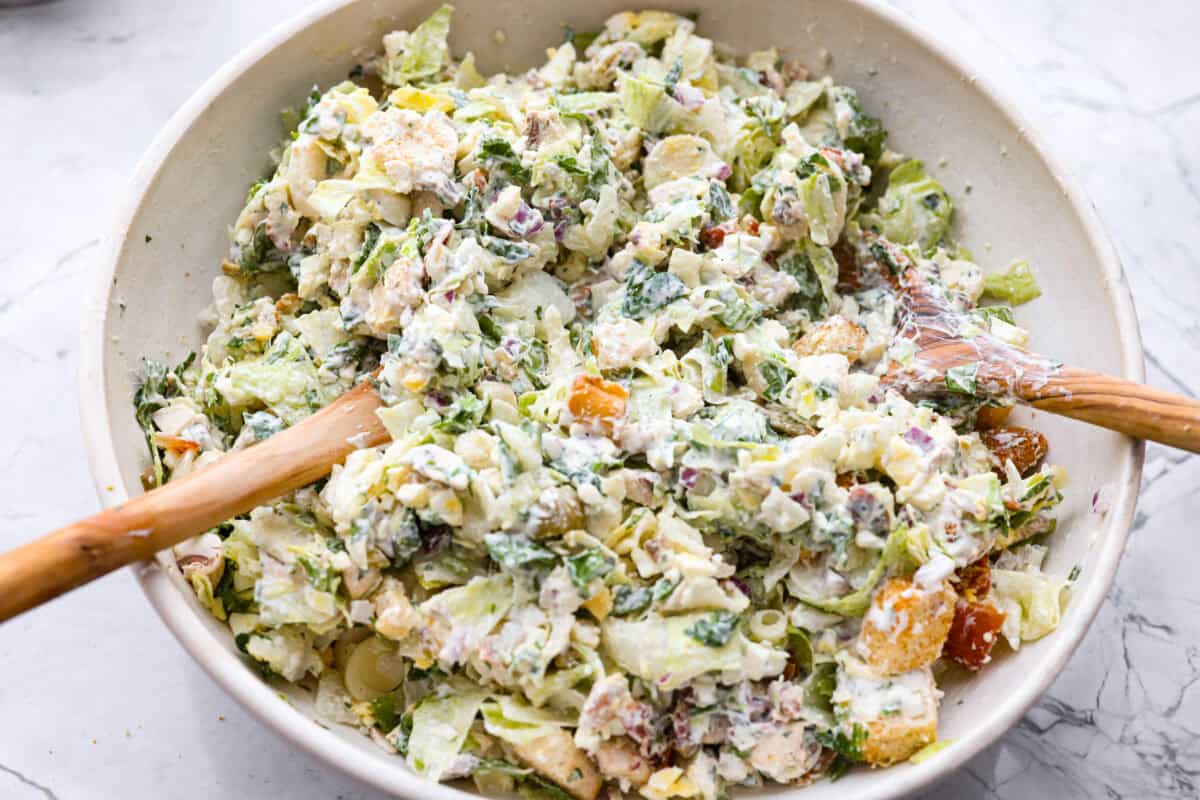 Ruth's Chris chopped salad is a steakhouse legend, and now you can make it at home for a fraction of the price. Crisp greens, smoky bacon, bold blue cheese, and a tangy lemon basil dressing come together in one showstopping bowl that tastes just like the real thing. Chopped salad ingredients mixed with the dressing.