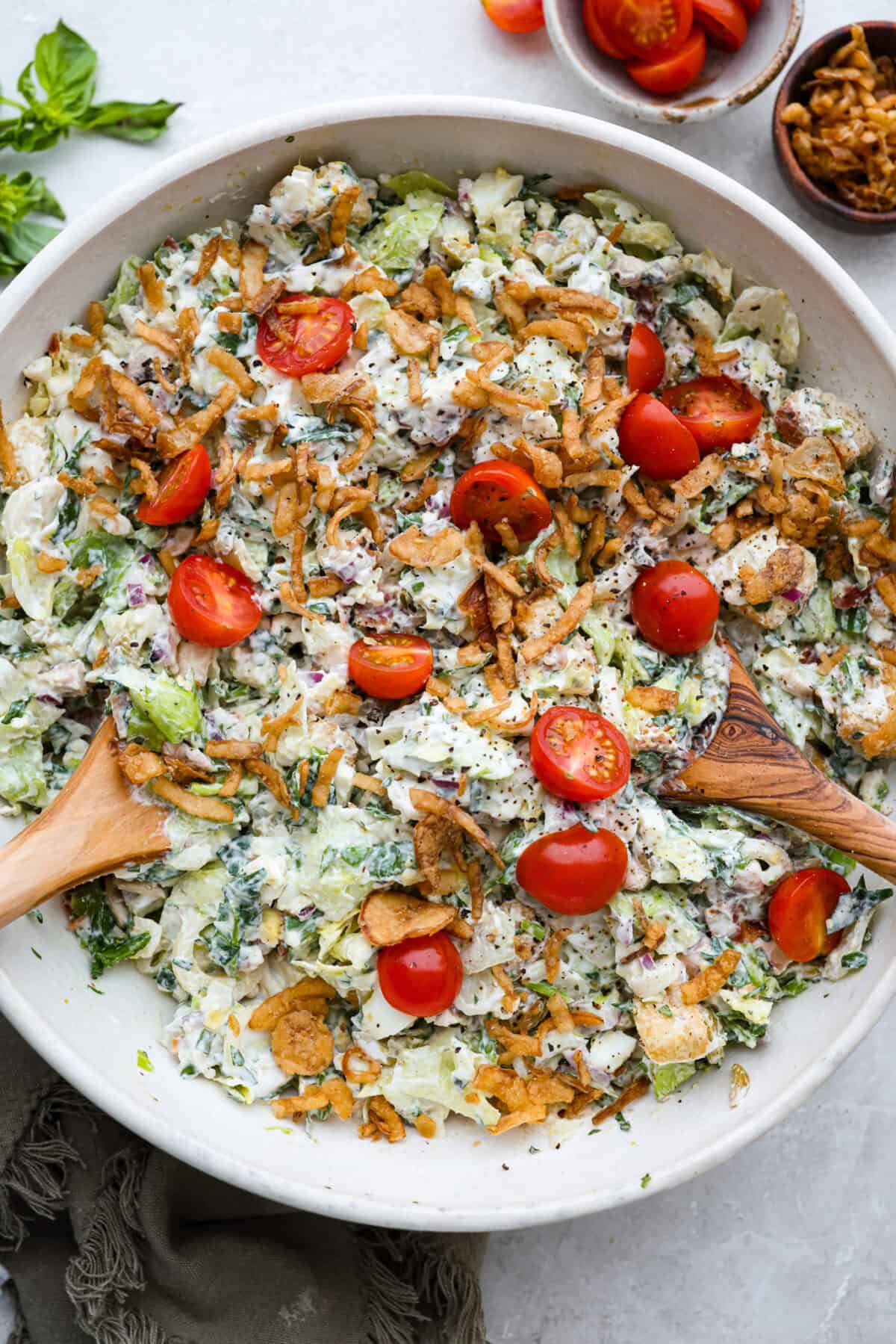 Ruth's Chris chopped salad is a steakhouse legend, and now you can make it at home for a fraction of the price. Crisp greens, smoky bacon, bold blue cheese, and a tangy lemon basil dressing come together in one showstopping bowl that tastes just like the real thing. Overhead shot of a large bowl of Ruth's Chris chopped salad.