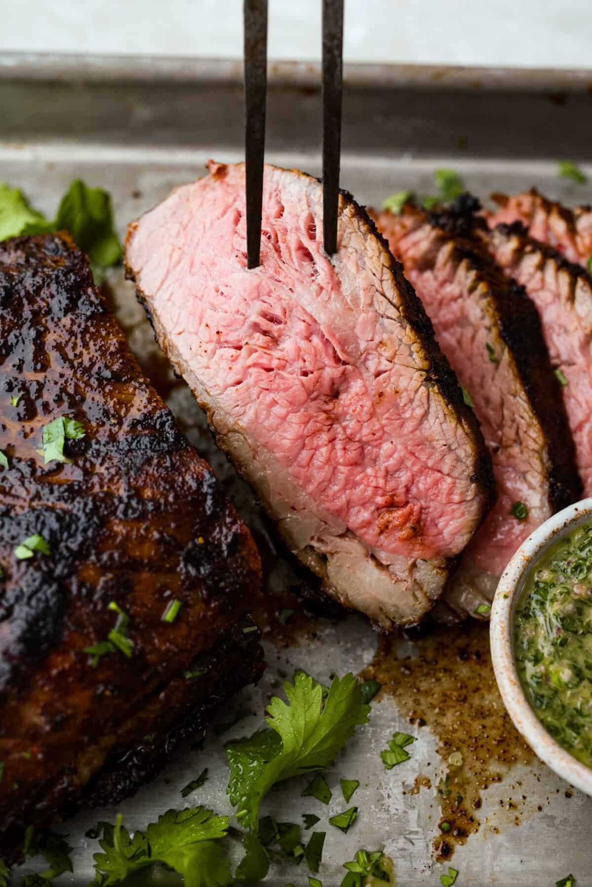 Santa Maria grilled tri-tip is juicy, smoky, and loaded with bold flavor from a delicious spice rub. Grilled until perfectly tender with a gorgeous crust, it’s an easy recipe that’s always a hit at cookouts and summer dinners. Close up of a slice of Santa Maria Tri-Tip.