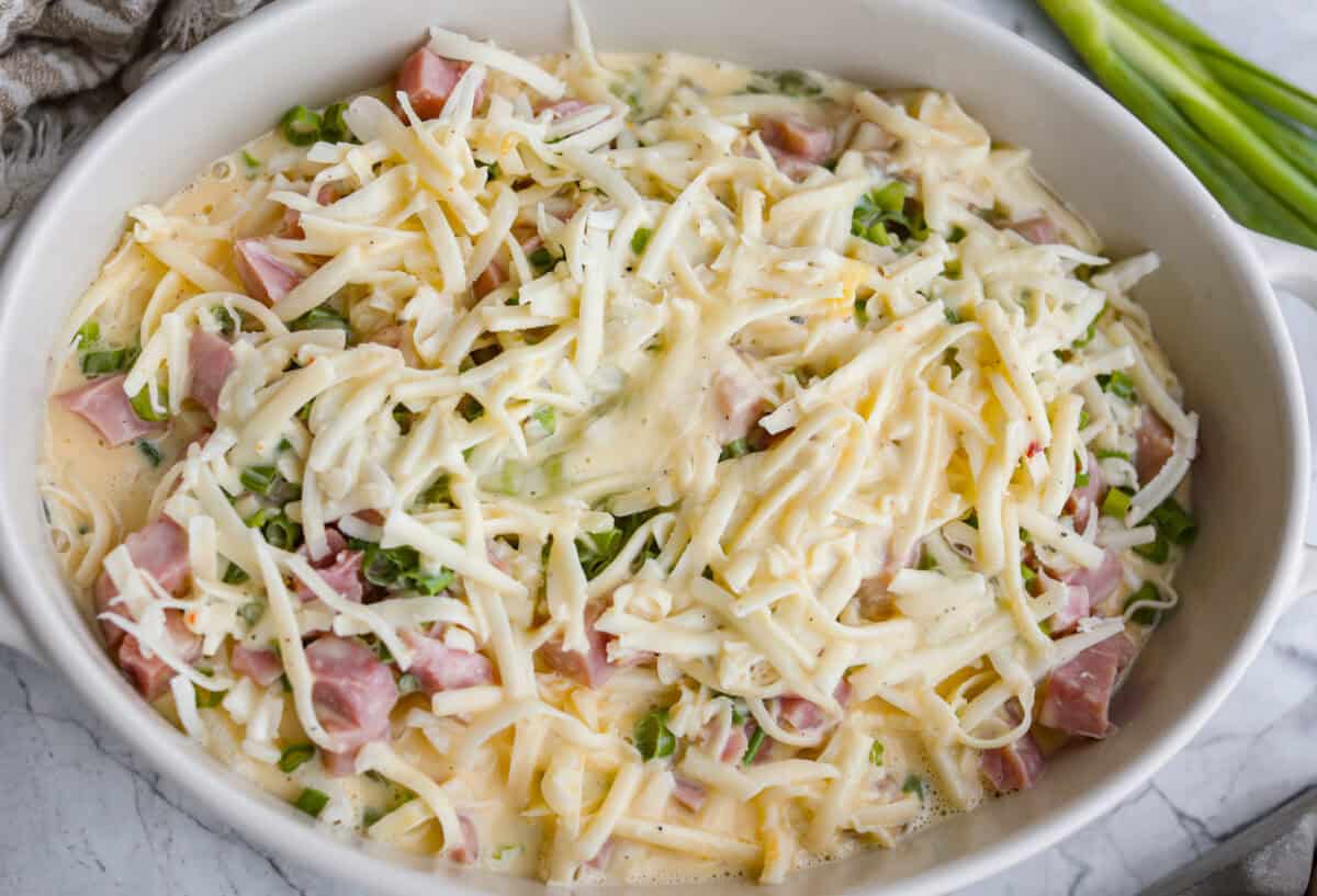 This farmer's casserole is my answer to summer mornings when the kids want cereal again, but I want them to eat something that will actually keep them full. It’s packed with protein, and it's easy to customize with fresh garden veggies. Egg mixture dumped over the top of the assembled farmer's casserole.