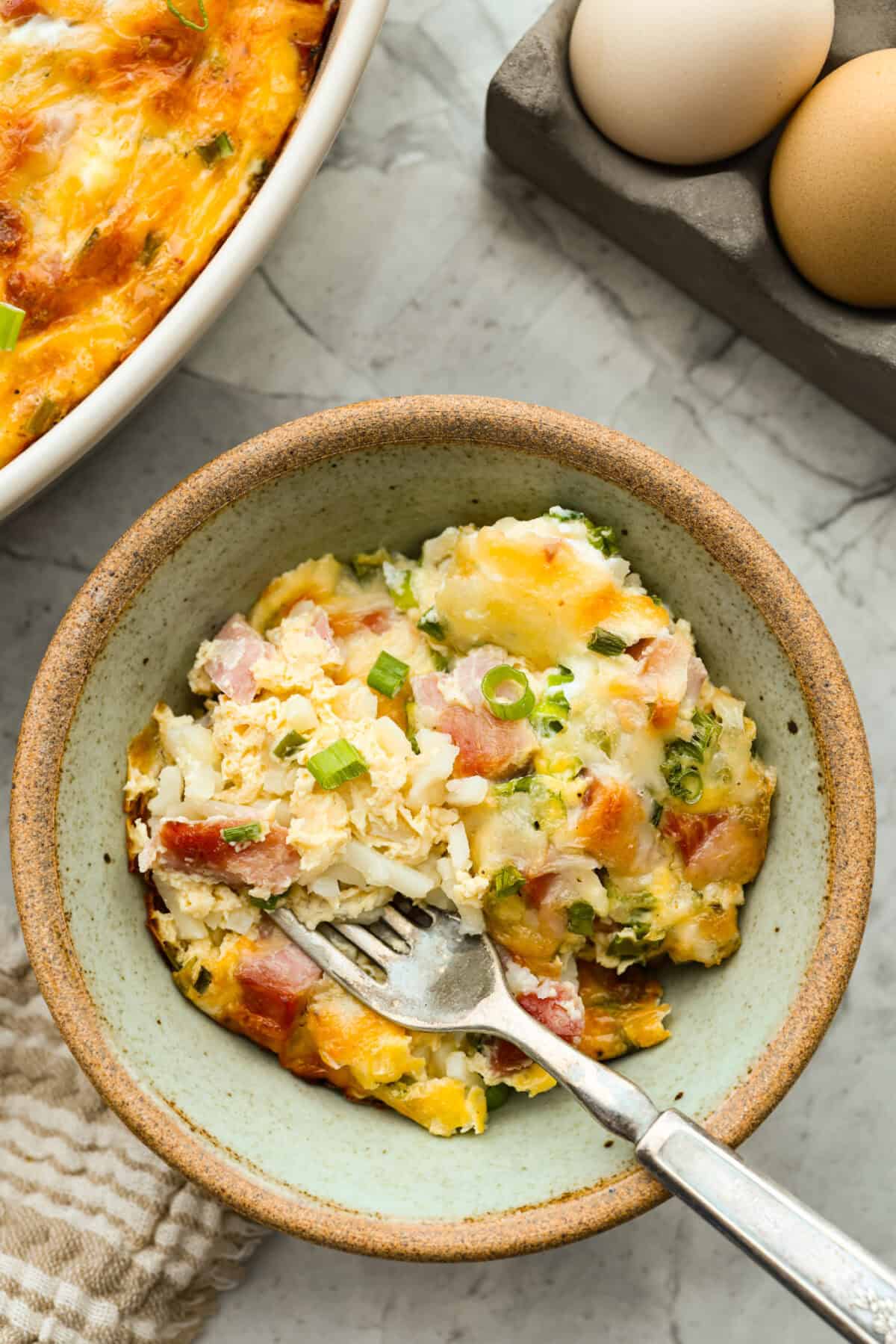 This farmer's casserole is my answer to summer mornings when the kids want cereal again, but I want them to eat something that will actually keep them full. It’s packed with protein, and it's easy to customize with fresh garden veggies. Serving of farmer's casserole in a bowl with a fork.