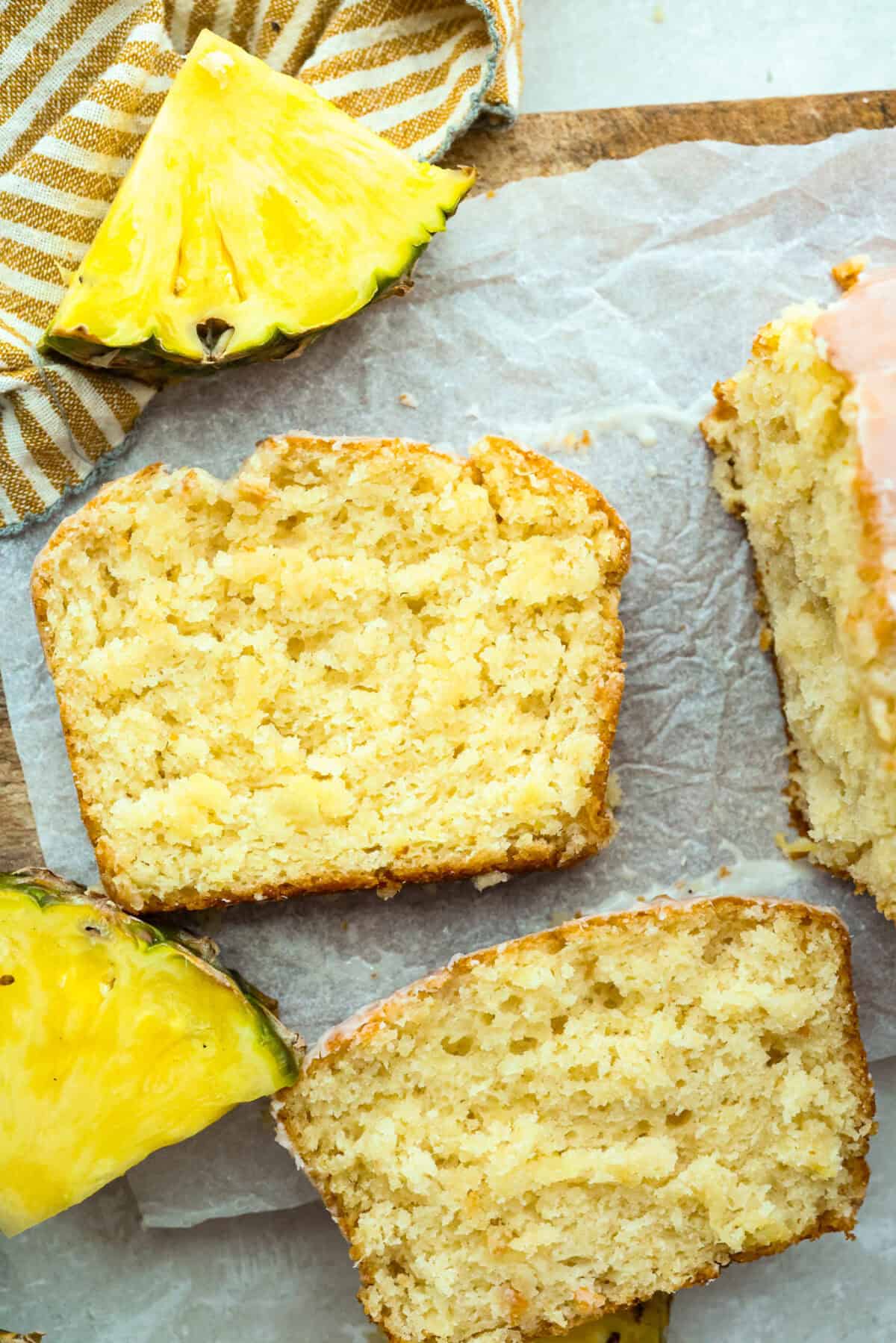 This glazed pineapple bread is what happens when a cozy quick bread meets a tropical vacation. Moist, tender, and drizzled with a sweet pineapple glaze, it's a taste of paradise in every bite. Top down shot of glazed pineapple bread slices.