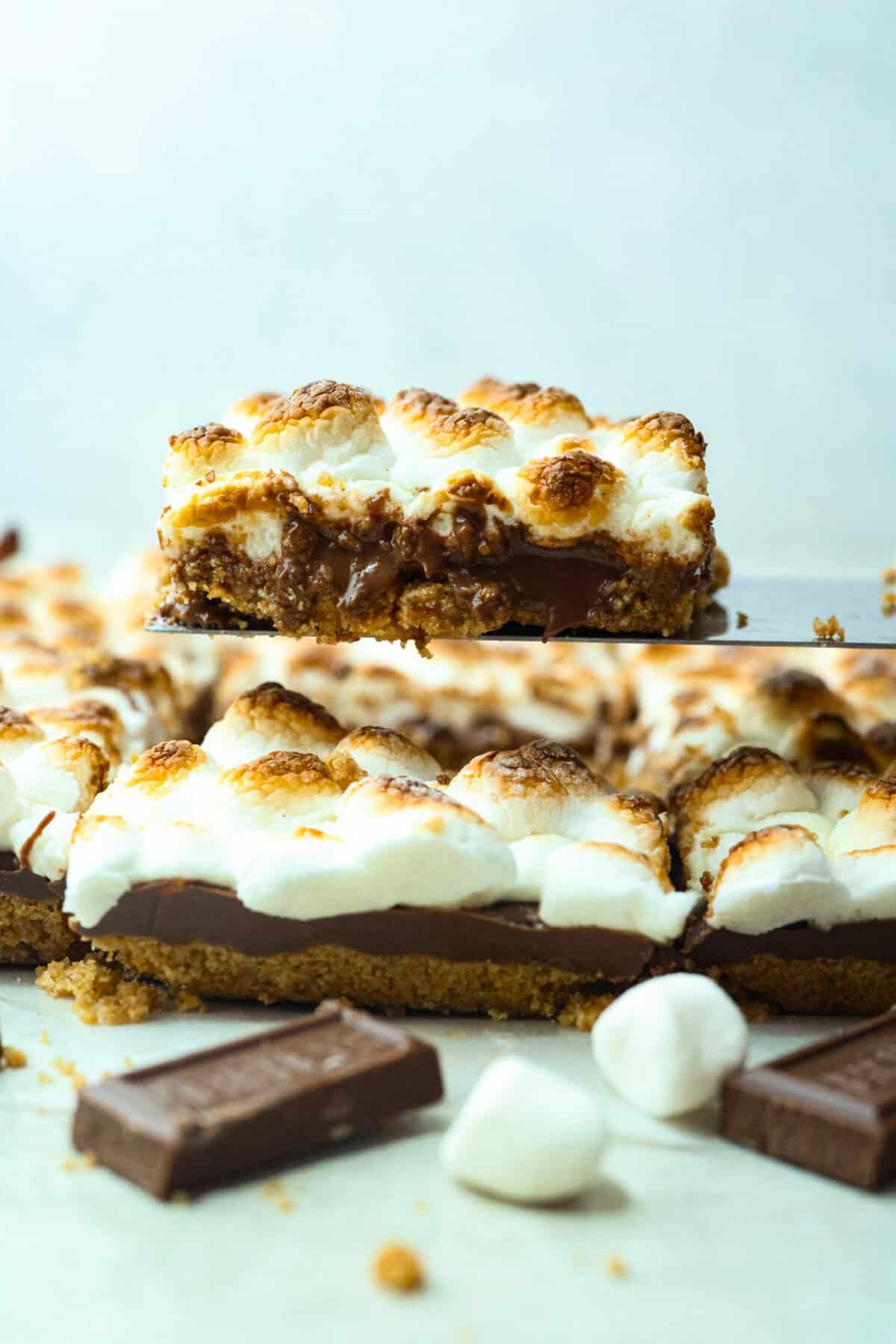 Remember the Starbucks s'mores bars everyone was obsessed with? They're back in homemade form! These easy bars have a buttery graham cracker crust, melty chocolate, and toasted marshmallows for the ultimate no-campfire-required treat. Side shot of someone lifting a Starbuck's s'mores bar out of the sheet of bars.