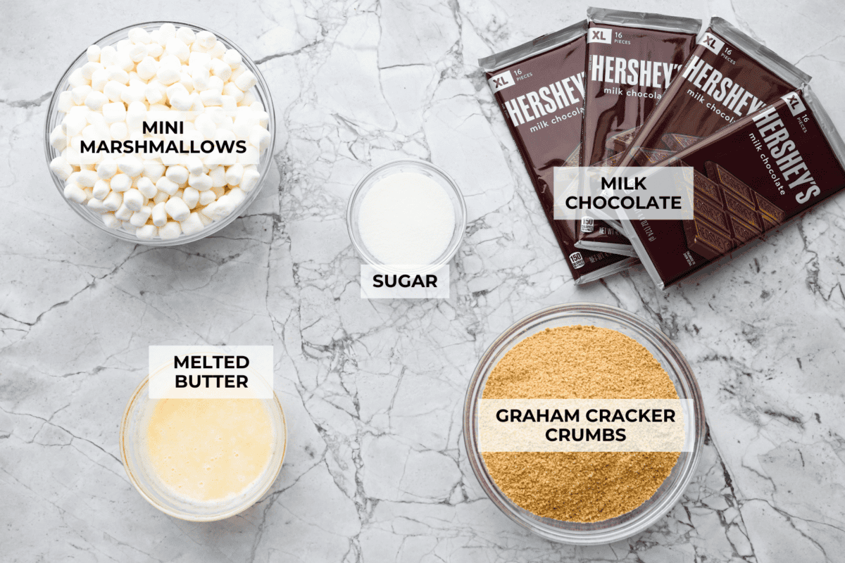 Remember the Starbucks s'mores bars everyone was obsessed with? They're back in homemade form! These easy bars have a buttery graham cracker crust, melty chocolate, and toasted marshmallows for the ultimate no-campfire-required treat. Overhead shot of labeled Starbuck's s'mores bars ingredients.