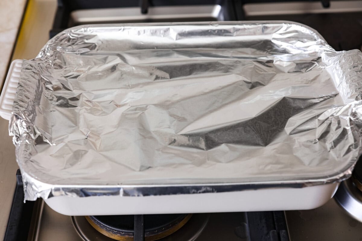 My coconut curry chicken bake proves one pan can do it all! Rice, chicken, and veggies bake in a creamy red curry coconut sauce, soaking up bold Thai flavor. Just 10 minutes of prep, then the oven takes over. Baking dish topped with tin foil ready to go in the oven.