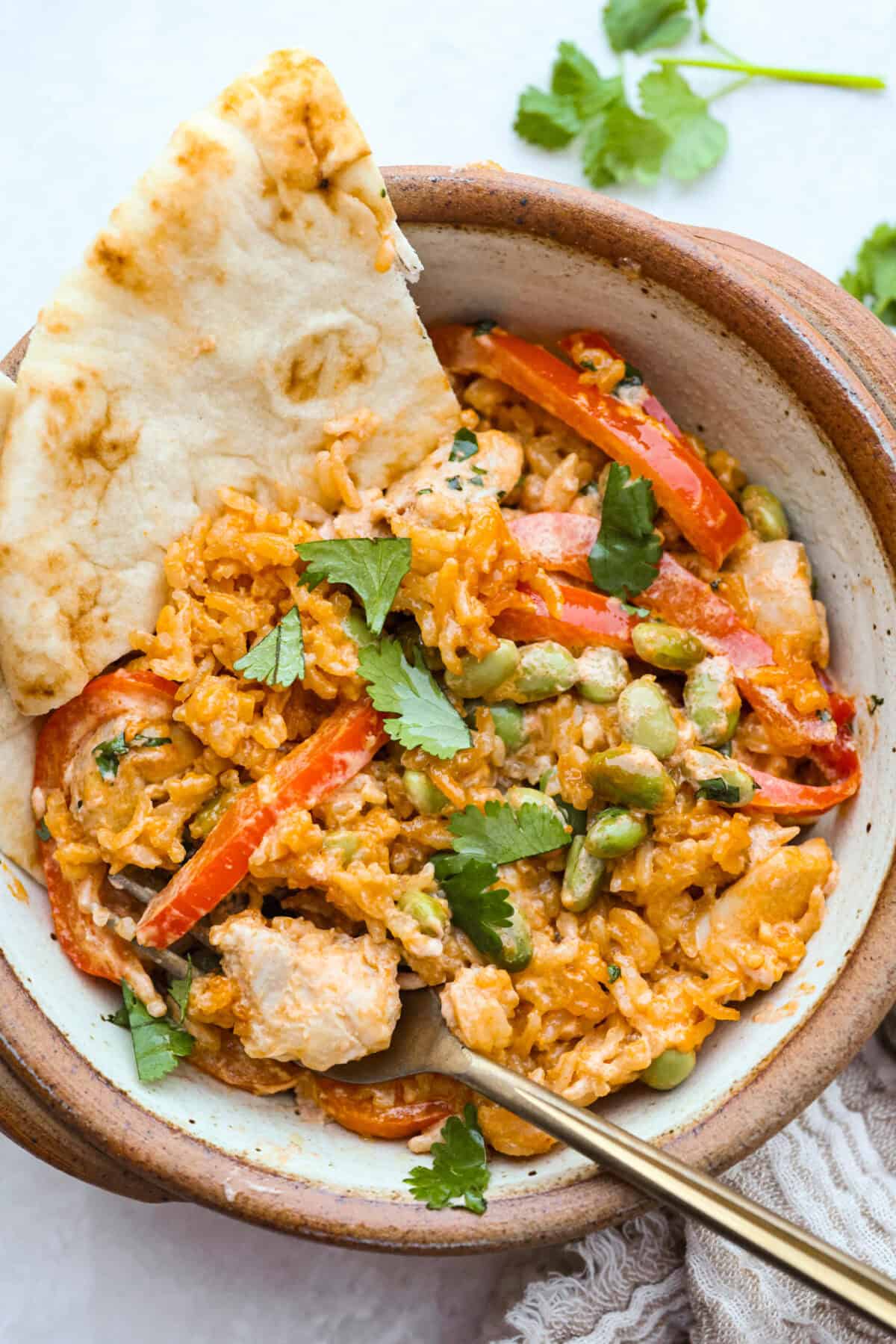 My coconut curry chicken bake proves one pan can do it all! Rice, chicken, and veggies bake in a creamy red curry coconut sauce, soaking up bold Thai flavor. Just 10 minutes of prep, then the oven takes over. Bowl of coconut curry chicken bake with some Naan bread on the side.