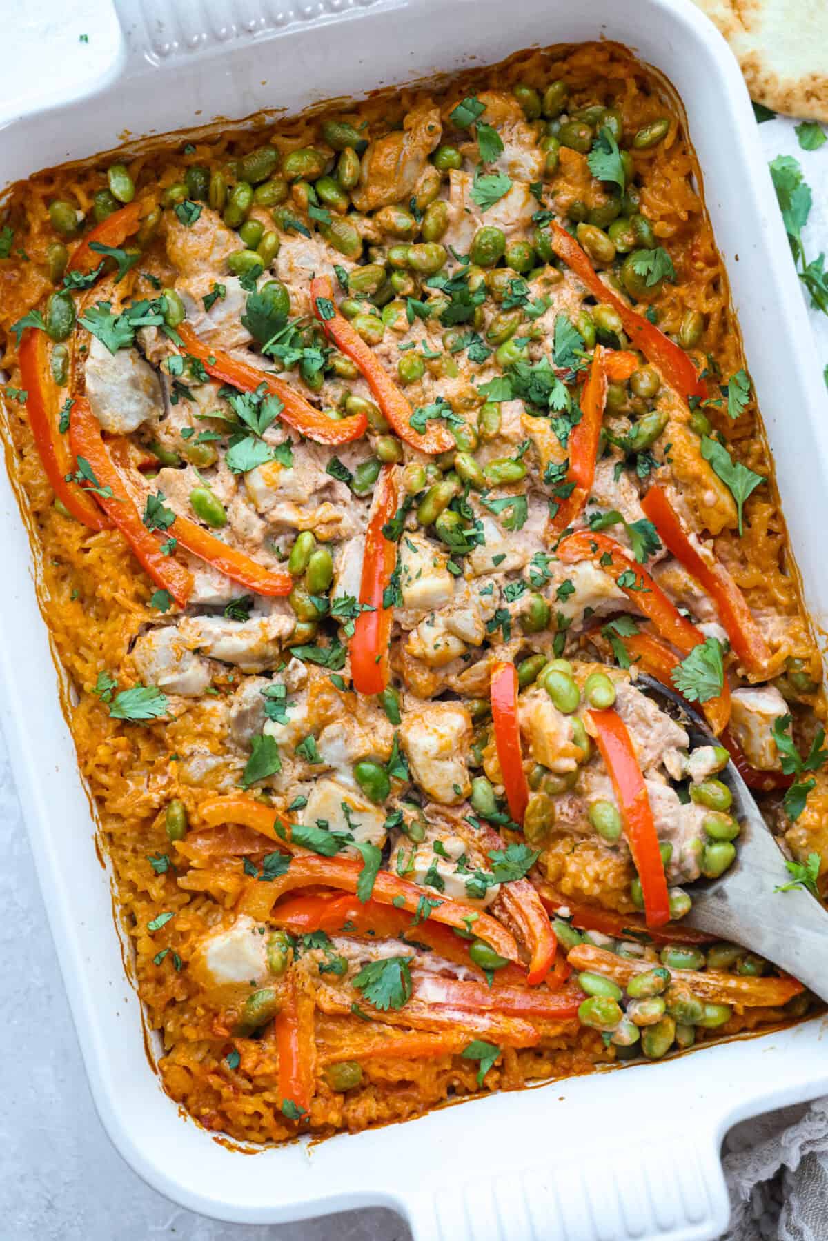 My coconut curry chicken bake proves one pan can do it all! Rice, chicken, and veggies bake in a creamy red curry-coconut sauce, soaking up bold Thai flavor with zero babysitting. Just 10 minutes of prep, then the oven takes over. Coconut curry chicken bake all cooked upin a baking dish.