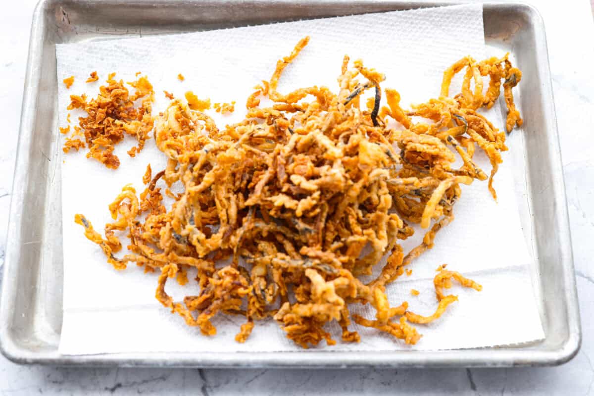 These crispy zucchini strings are golden, crunchy, and seriously hard to stop eating. Lightly battered and fried until perfectly crisp, they turn simple zucchini into an addictive snack or side dish that everyone will reach for first. Zucchini strings on a paper towel after cooking.