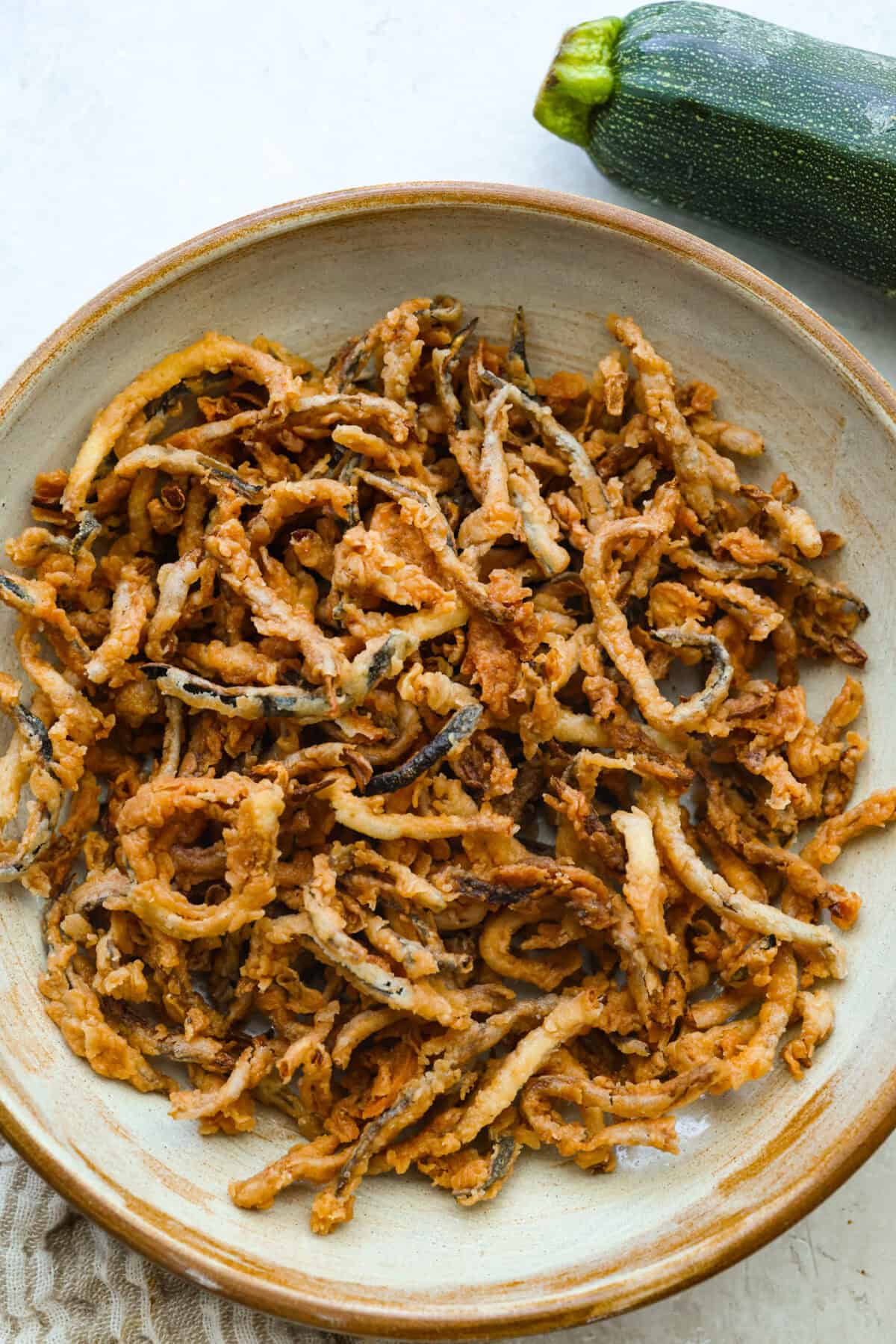 These crispy zucchini strings are golden, crunchy, and seriously hard to stop eating. Lightly battered and fried until perfectly crisp, they turn simple zucchini into an addictive snack or side dish that everyone will reach for first. Bowl of crispy zucchini strings.