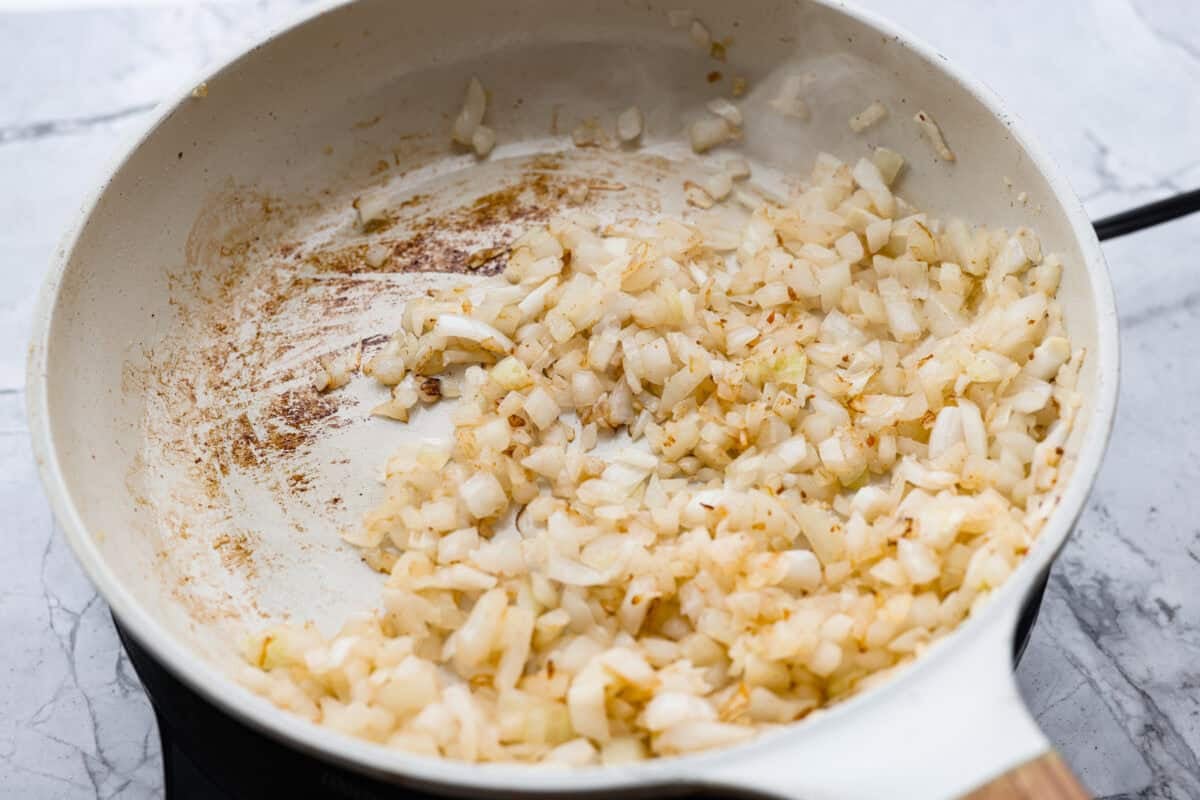 Onions cooking in a skillet with the bacon grease. 
