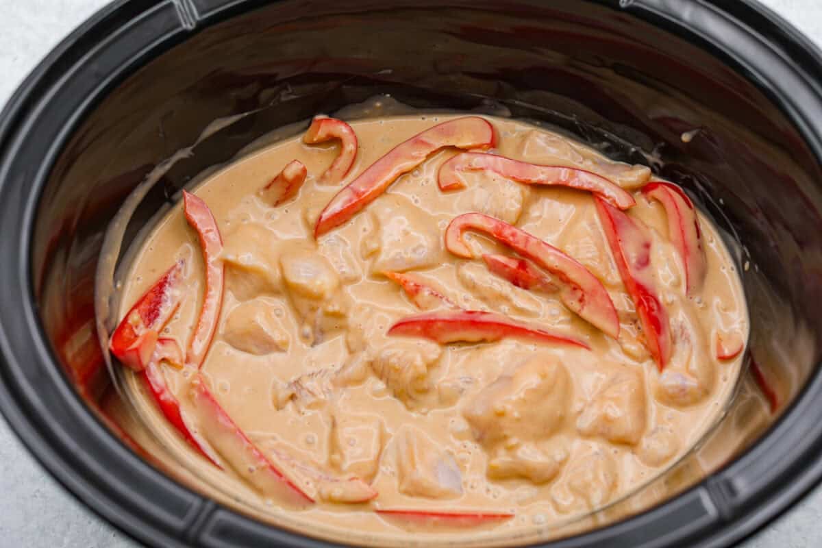You asked, I listened! This slow cooker Thai peanut chicken got a serious glow-up! The sauce is creamy, savory, a little sweet, and packed with peanut coconut flavor. I’d drink it with a straw if that were socially acceptable, but spooning it over rice, noodles or adding it to lettuce wraps is probably the better dinner move. Sauce added to the peppers and chicken in the slow cooker.