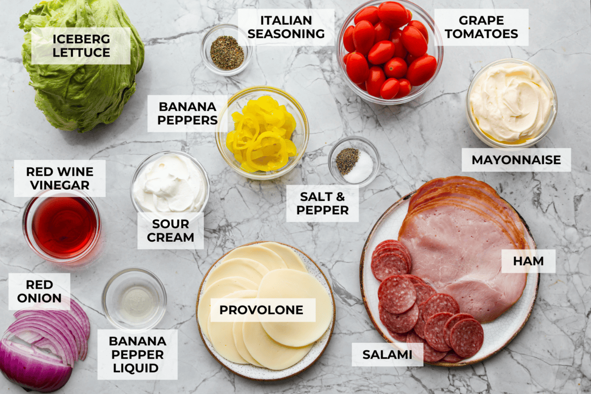 If you're a fan of deli sandwiches, you will love this sub in a tub dip! Made with deli meats, cheese, crisp veggies, and a creamy tangy dressing, it tastes just like your favorite sandwich shop sub in dip form! Overhead shot of labeled ingredients.