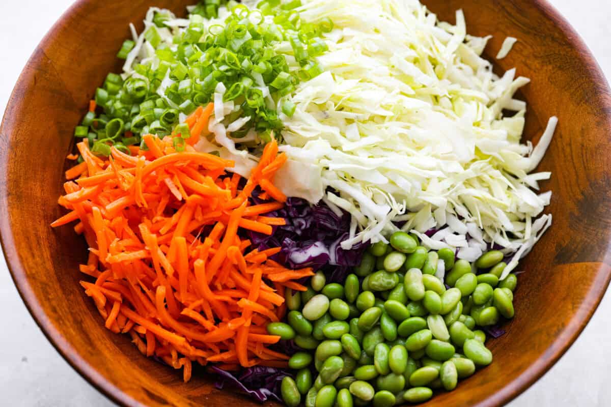 Asian ramen salad is colorful, crunchy, and packed with fresh flavor! It’s made with crisp cabbage, vegetables, toasted ramen noodles, almonds, and a sweet and savory homemade dressing. Sliced up veggies for the salad in a bowl.