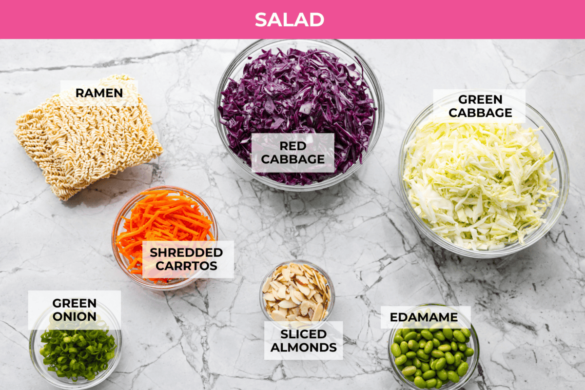 Asian ramen salad is colorful, crunchy, and packed with fresh flavor! It’s made with crisp cabbage, vegetables, toasted ramen noodles, almonds, and a sweet and savory homemade dressing. Overhead shot of labeled Asian ramen salad ingredients.