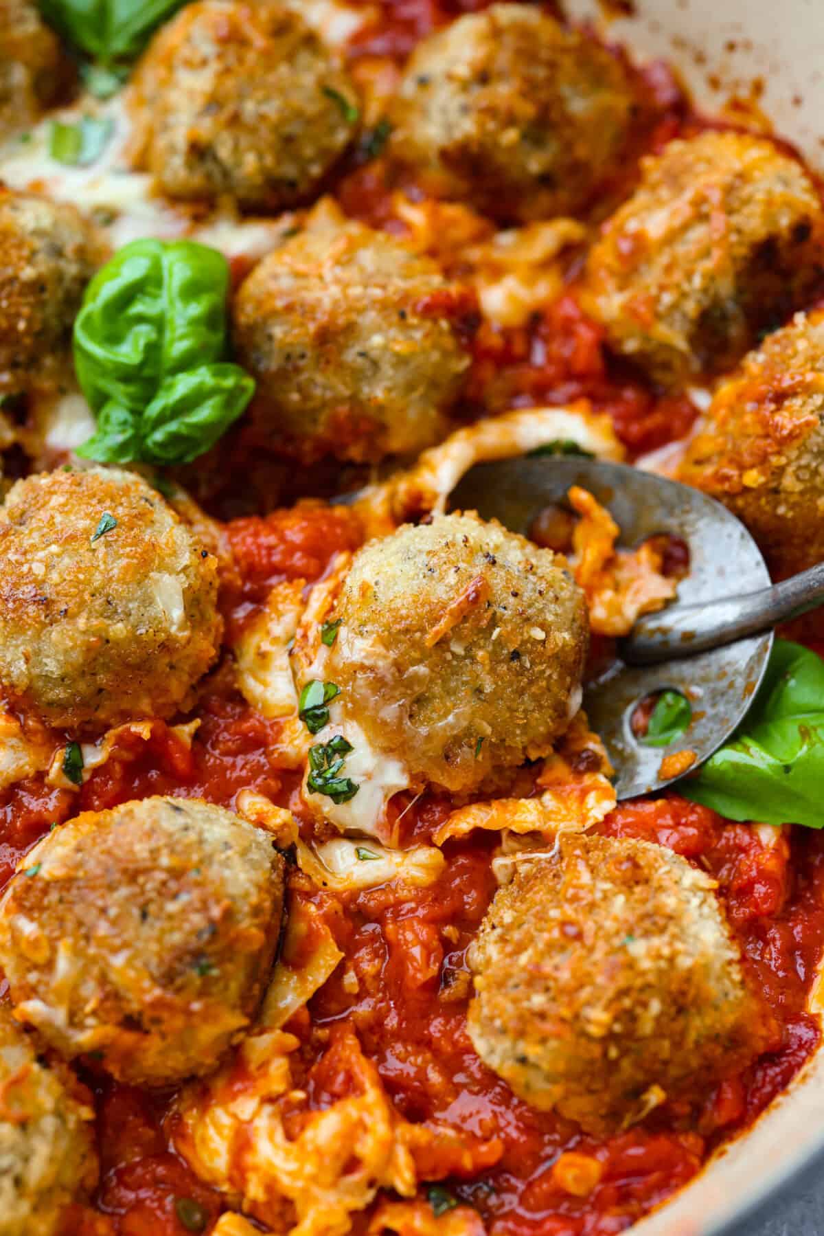 Chicken parmesan meatballs bring all the best parts of chicken parmesan together in one skillet. Think tender chicken meatballs, crispy Parmesan breadcrumbs, saucy marinara, and lots of melted mozzarella. Close up picture of the chicken parmesan meatballs all browned and baked and ready to eat.