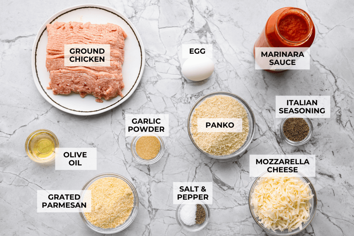 Chicken parmesan meatballs bring all the best parts of chicken parmesan together in one skillet. Think tender chicken meatballs, crispy Parmesan breadcrumbs, saucy marinara, and lots of melted mozzarella. Overhead shot of labeled chicken parmesan meatballs ingredients.