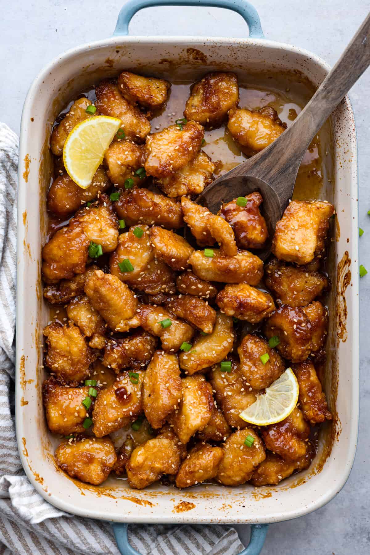 Chinese lemon chicken is lightly fried until golden, then baked in the sticky homemade sauce packed with bright lemon flavor. Make a full take-out-style meal at home with my easy fried rice, cream cheese wontons, and chow mein! Overhead shot of the Chinese lemon chicken all cooked and ready to eat.
