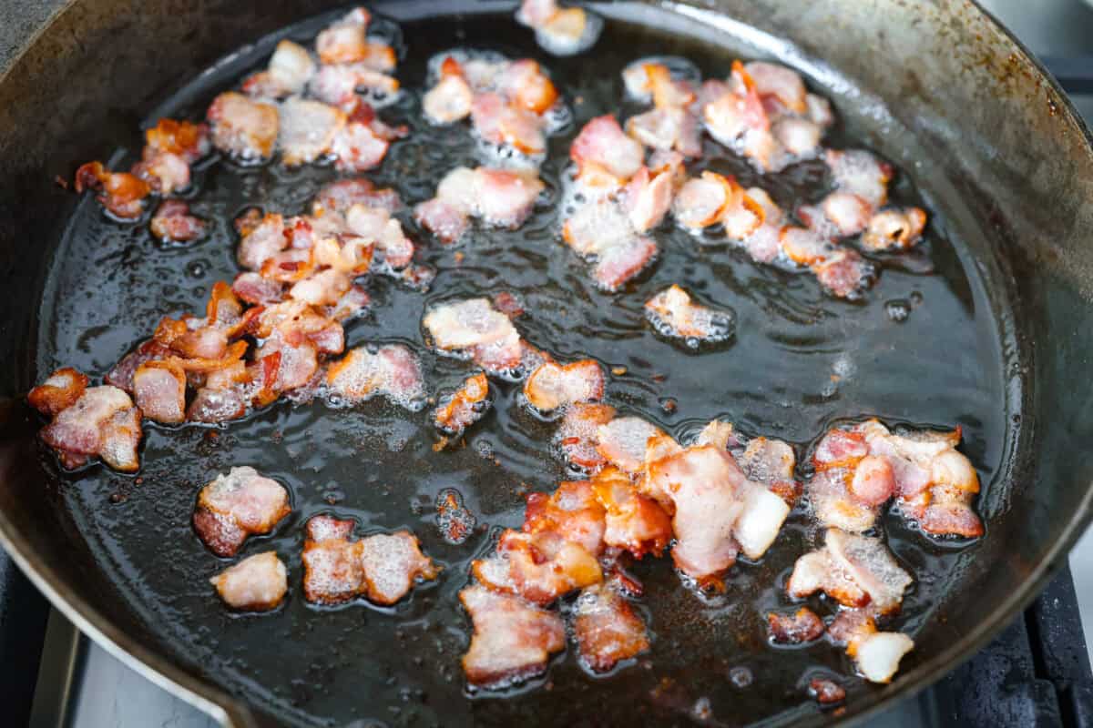 Cowboy meatballs bring big, bold flavors to a classic dinner favorite! Packed with cheesy goodness and spices, they’re simmered in a smoky BBQ sauce with crispy bacon and a little kick from Rotel. So delicious you’ll want to scoop up every last drop. Bacon pieces cooking in a skillet.