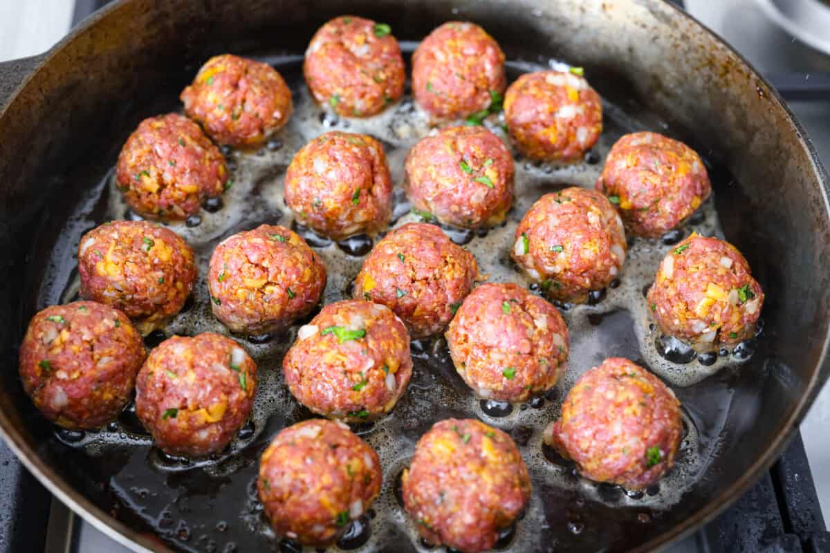 Cowboy meatballs bring big, bold flavors to a classic dinner favorite! Packed with cheesy goodness and spices, they’re simmered in a smoky BBQ sauce with crispy bacon and a little kick from Rotel. So delicious you’ll want to scoop up every last drop. Meatballs cooking in the bacon grease.
