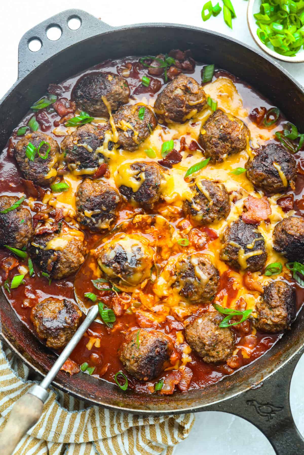Cowboy meatballs bring big, bold flavors to a classic dinner favorite! Packed with cheesy goodness and spices, they’re simmered in a smoky BBQ sauce with crispy bacon and a little kick from Rotel. So delicious you’ll want to scoop up every last drop. Skillet with cheesy, saucy cowboy meatballs.
