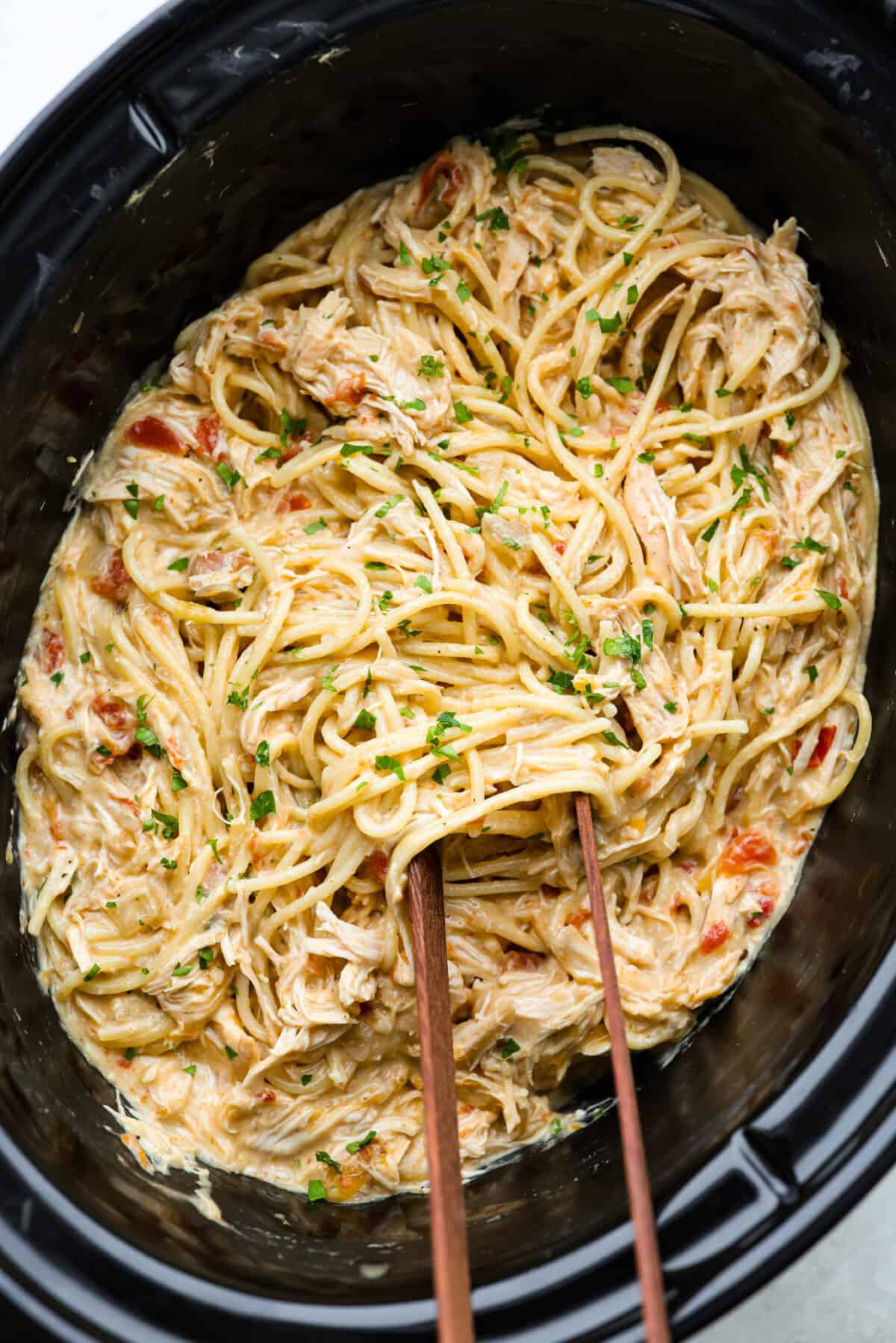 This crockpot chicken spaghetti will have everyone running to the dinner table! The slow cooker does the work while the chicken becomes tender and flavorful, then it's tossed with spaghetti, melty cheese, and a creamy sauce. Overhead shot of crockpot chicken spaghetti.