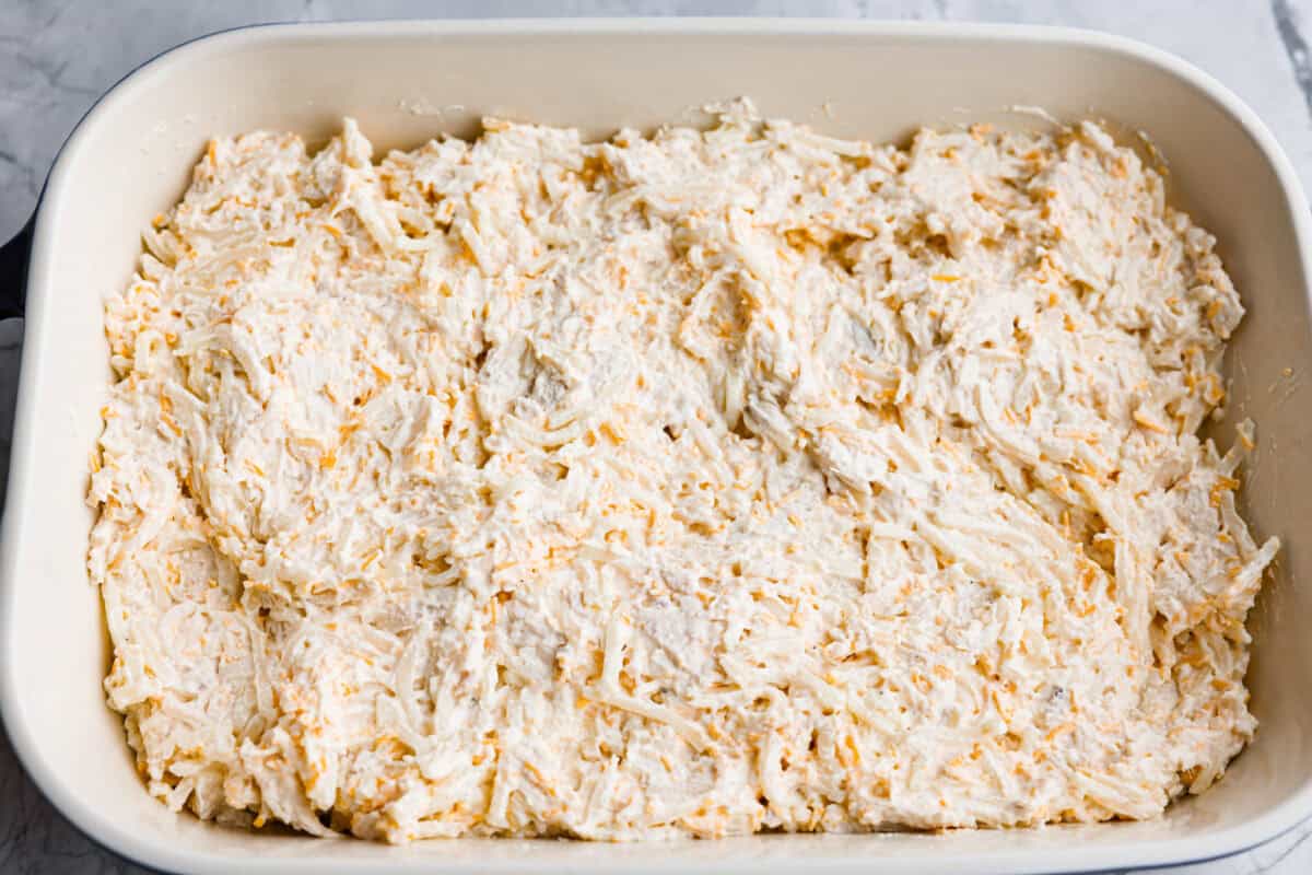 My funeral potato and chicken casserole turns the classic cheesy side dish into a complete dinner. It’s creamy, comforting, and packed with tender chicken, potatoes, and plenty of cheese. Fully combined casserole ingredients mixed together and spread around the bottom of a baking dish.