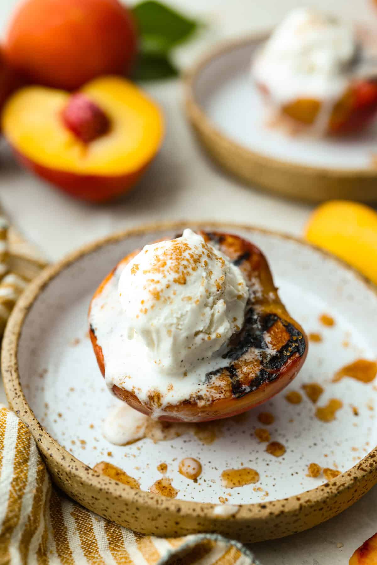 Grilled peaches are one of my favorite ways to turn ripe summer fruit into an easy dessert. The grill brings out their natural sweetness and adds just a little smoky flavor. Serve them warm with vanilla ice cream for a simple treat that feels extra special. Grilled peaches topped with ice cream.