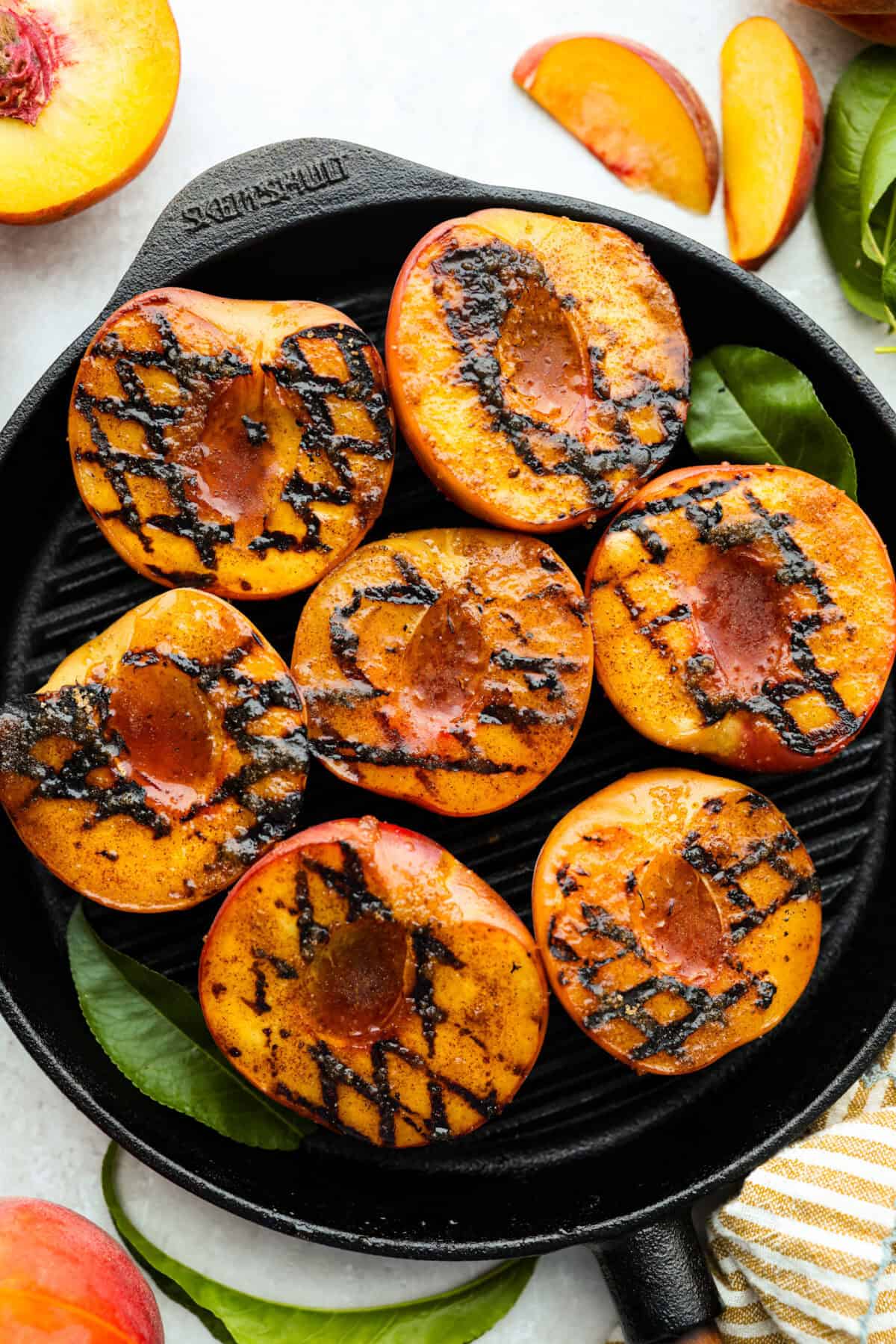 Grilled peaches are one of my favorite ways to turn ripe summer fruit into an easy dessert. The grill brings out their natural sweetness and adds just a little smoky flavor. Serve them warm with vanilla ice cream for a simple treat that feels extra special. Grilled peaches with grill marks on a grilling pan.
