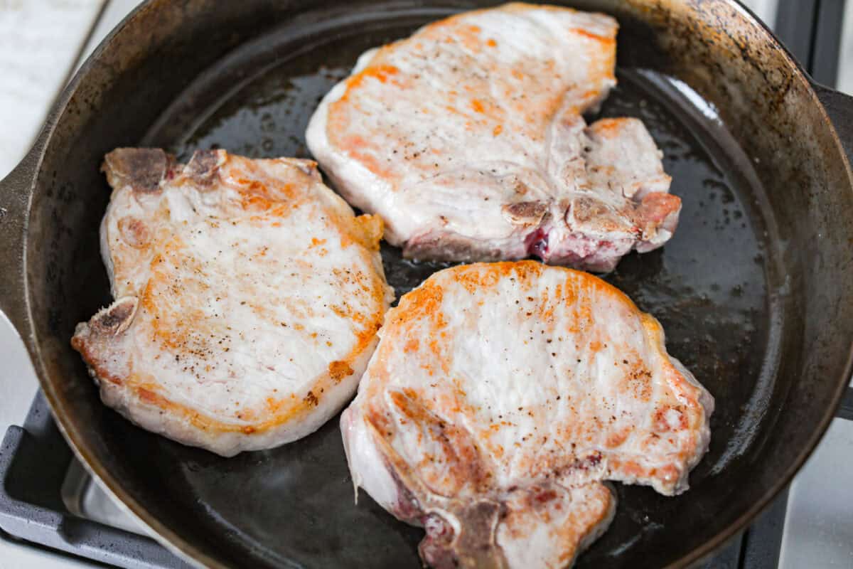 Marry Me pork chops are the kind of dinner that earns its name! Tender pork chops are simmered in a rich, creamy Parmesan sauce with garlic, Italian herbs, and sweet, tangy sun-dried tomatoes. One bite and you’ll get why they’re worth proposing over. Searing pork chops in a skillet.