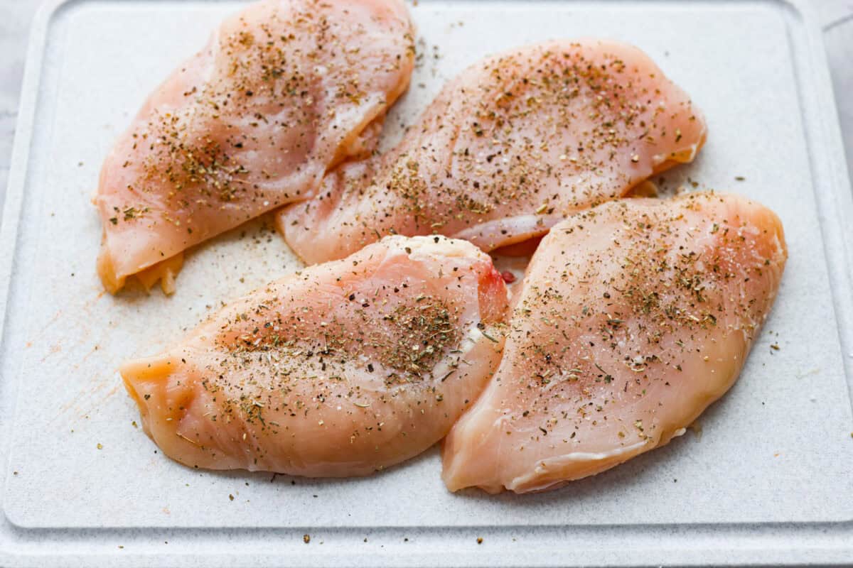 Creamy pepperoncini chicken is an easy one-skillet dinner packed with flavor! Tender chicken is smothered in a rich Parmesan cream sauce with bell peppers and tangy pepperoncini. It's the perfect balance of creamy, savory, and zesty flavor. Chicken breasts on a cutting board and seasoned.