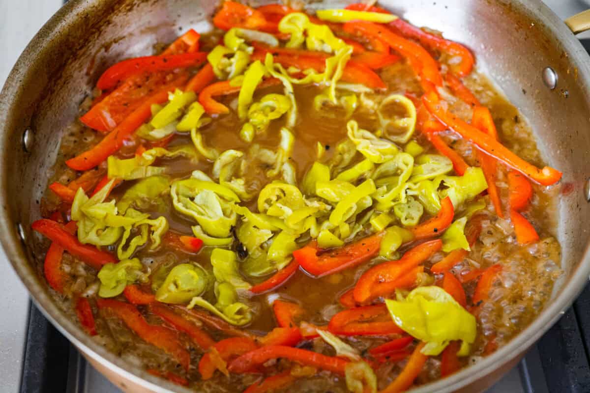 Creamy pepperoncini chicken is an easy one-skillet dinner packed with flavor! Tender chicken is smothered in a rich Parmesan cream sauce with bell peppers and tangy pepperoncini. It's the perfect balance of creamy, savory, and zesty flavor. Pepperoncini's cooking in a skillet with the peppers and chicken broth.