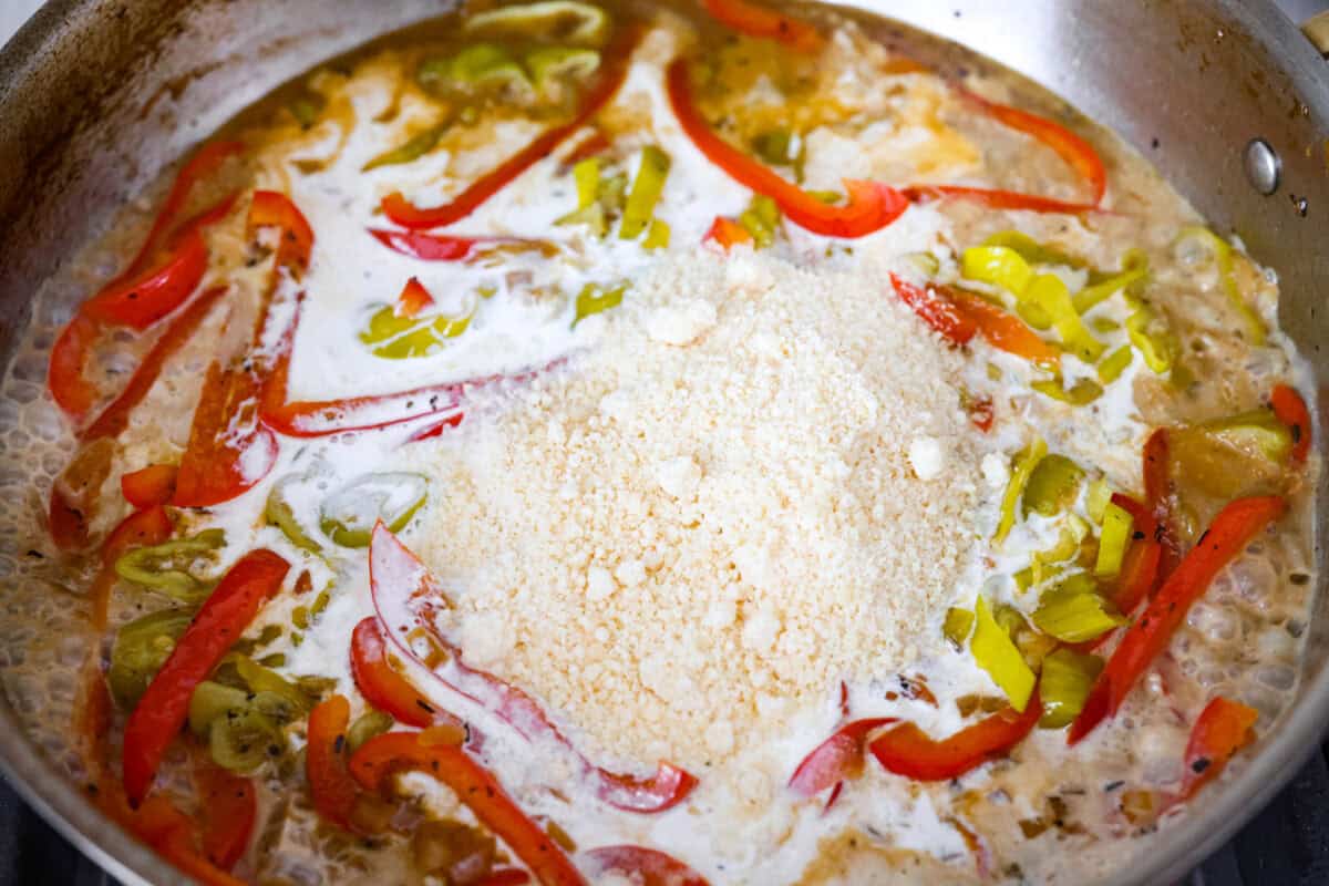 Creamy pepperoncini chicken is an easy one-skillet dinner packed with flavor! Tender chicken is smothered in a rich Parmesan cream sauce with bell peppers and tangy pepperoncini. It's the perfect balance of creamy, savory, and zesty flavor. Parmesan cheese and cream added to the skillet to make the creamy pepperoncini chicken sauce.