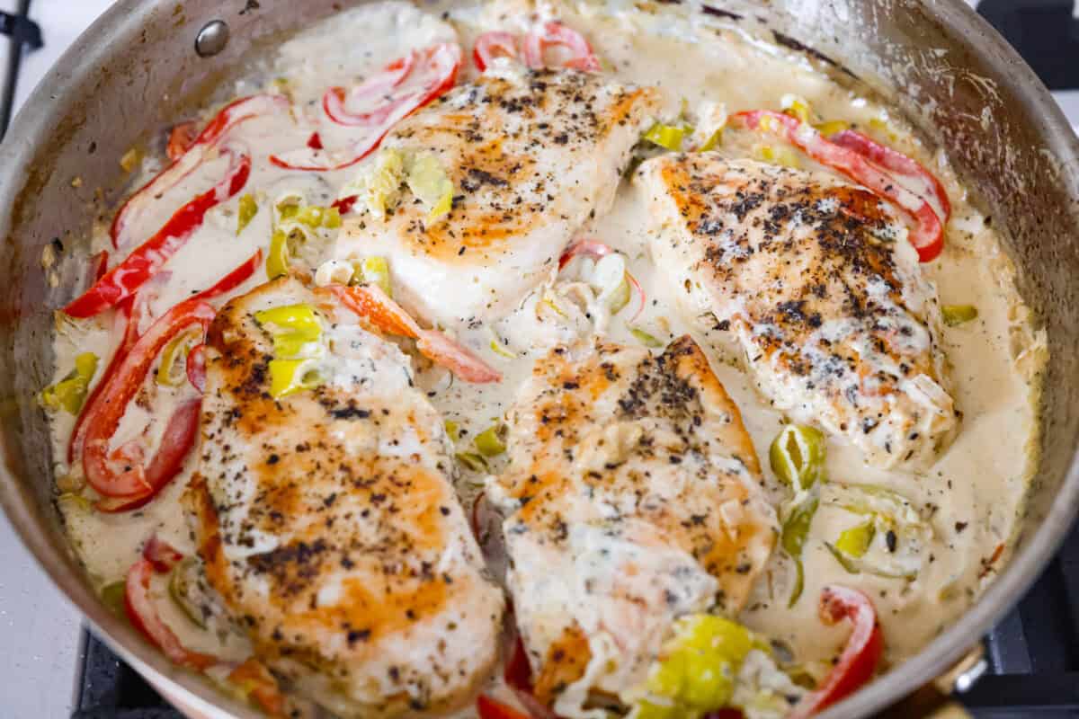 Creamy pepperoncini chicken is an easy one-skillet dinner packed with flavor! Tender chicken is smothered in a rich Parmesan cream sauce with bell peppers and tangy pepperoncini. It's the perfect balance of creamy, savory, and zesty flavor. Cooked chicken breasts added back to the skillet to cook in the creamy pepperoncini chicken sauce.