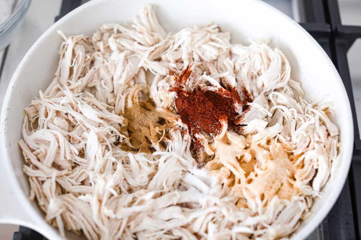 Shredded chicken tacos turn cooked chicken into juicy, flavorful tacos with salsa, lime, and a few simple seasonings. Use rotisserie chicken or choose from four easy ways to cook and shred your own. Shredded chicken and seasonings added to the skillet.