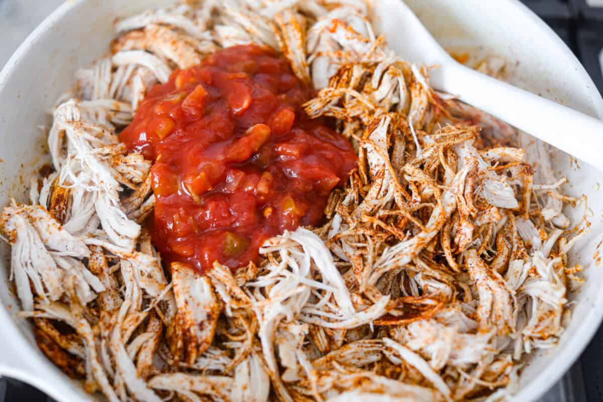 Shredded chicken tacos turn cooked chicken into juicy, flavorful tacos with salsa, lime, and a few simple seasonings. Use rotisserie chicken or choose from four easy ways to cook and shred your own. Salsa, lime juice, and chicken broth added to the chicken in the skillet.