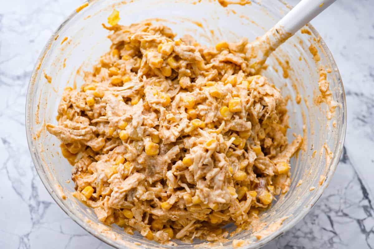 These street corn chicken enchiladas are creamy, cheesy, and packed with zesty flavor. An easy 40-minute dinner the whole family will love. Chicken added, corn and cheese combined with some of the sauce.
