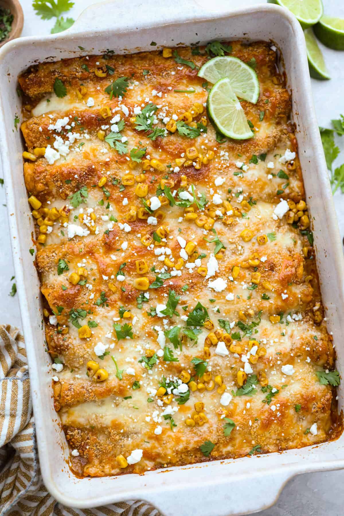 These street corn chicken enchiladas are creamy, cheesy, and packed with zesty flavor. An easy 40-minute dinner the whole family will love. Baking dish with street corn chicken enchiladas.