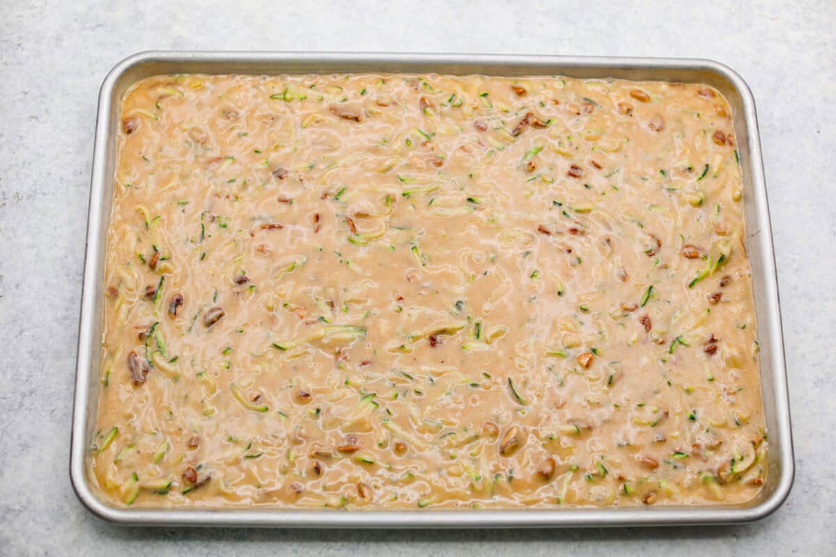 These zucchini bars with brown butter frosting are one of my favorite ways to use up all the zucchini from my garden. The bars are soft, warmly spiced, and incredibly moist, while the nutty brown butter frosting makes every bite taste extra special. Zucchini bars batter spread out in a jelly roll pan.
