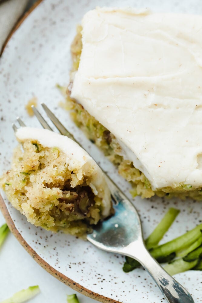 Zucchini Bars with Brown Butter Frosting is deliciously moist and absolutely heavenly. This is one of the best ways to use up those extra summer zucchini. Using a fork to cut the zucchini bar.